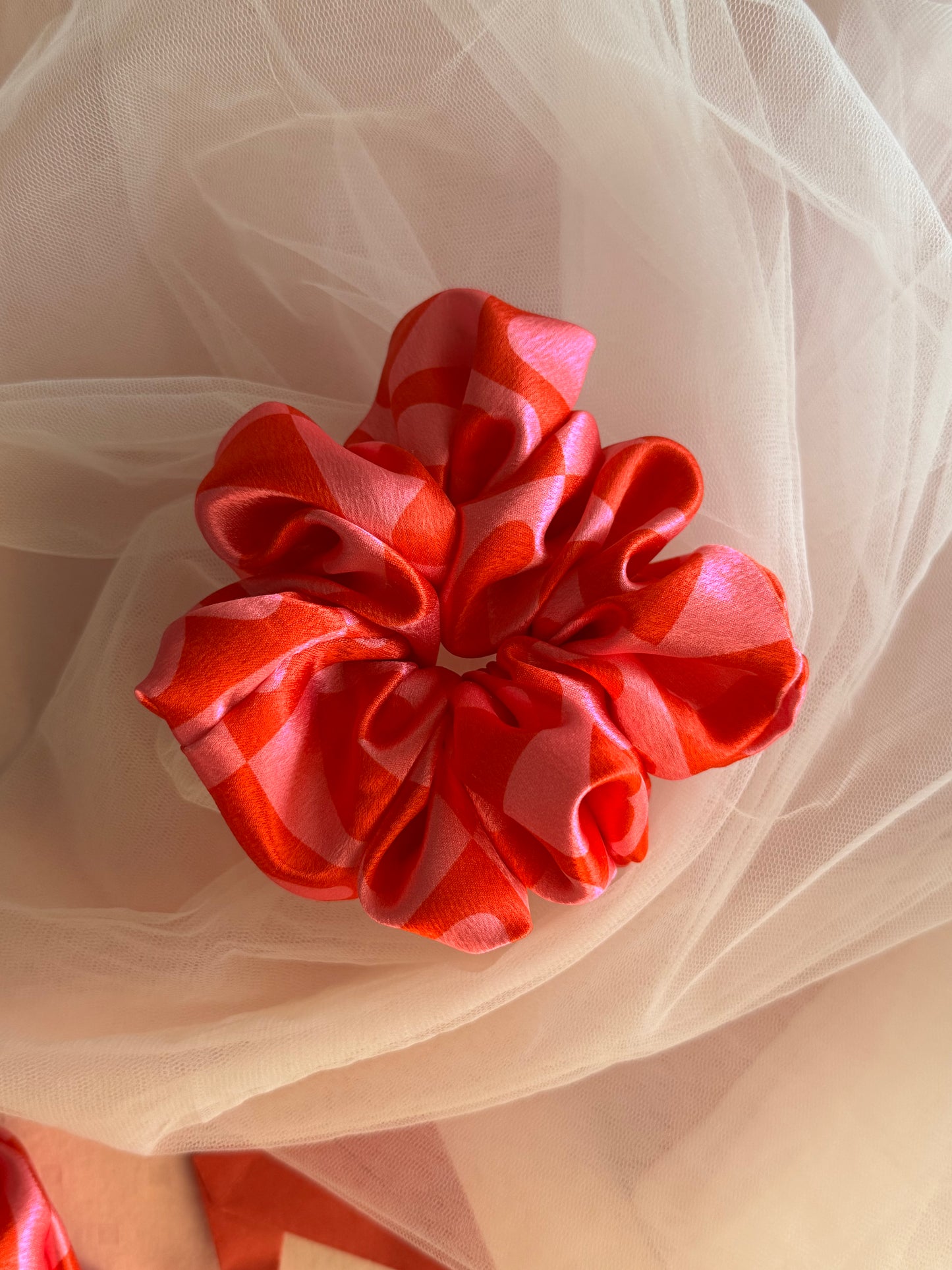 A charming pink satin scrunchie with a playful heart print, made from soft printed satin fabric to prevent hair damage—perfect for ponytails, buns, and stylish everyday hair accessories