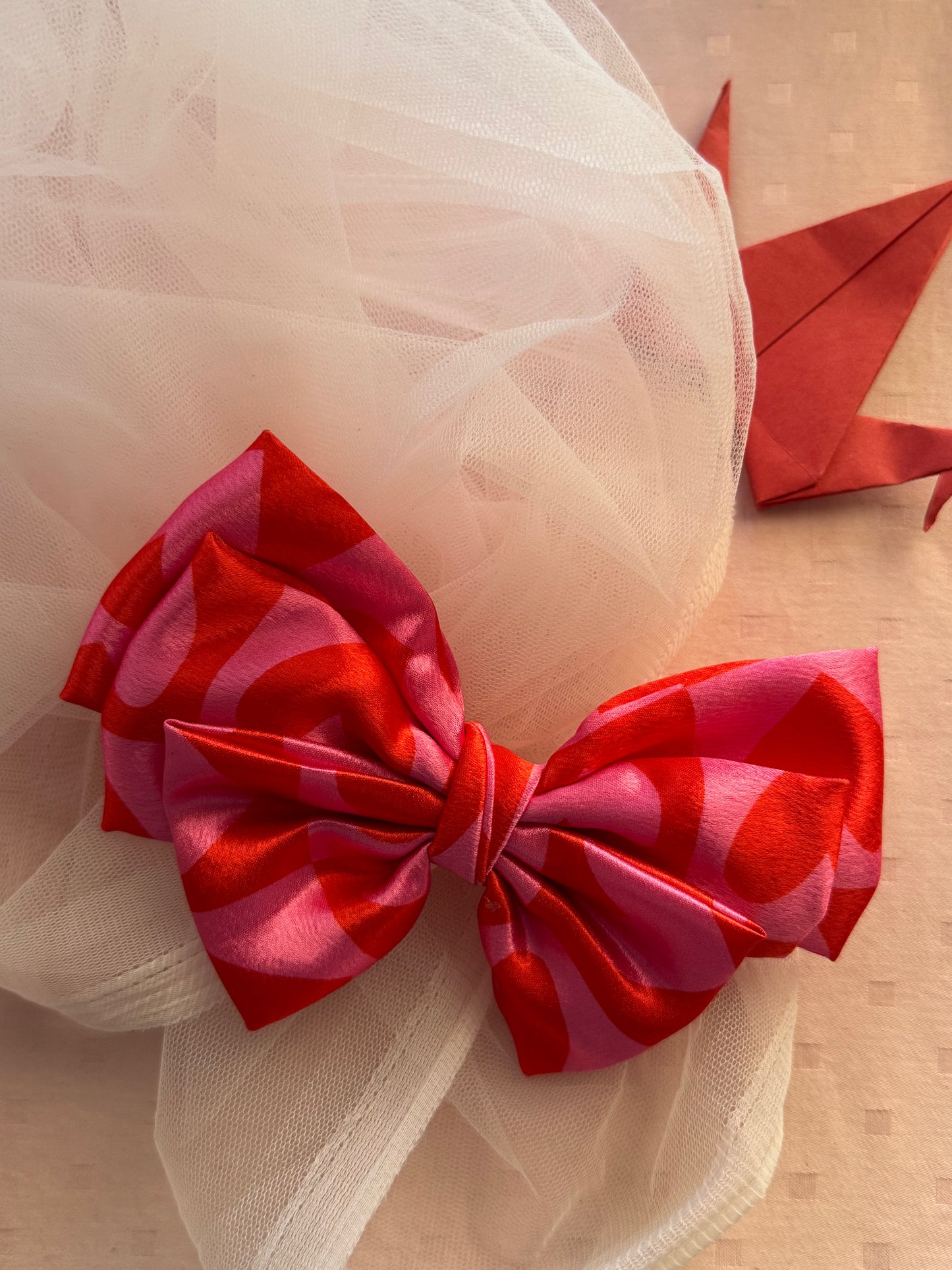 Love Struck Hair Bow Clip - Front view of a large pink satin hair bow with heart prints, radiating love and playfulness for a charming look