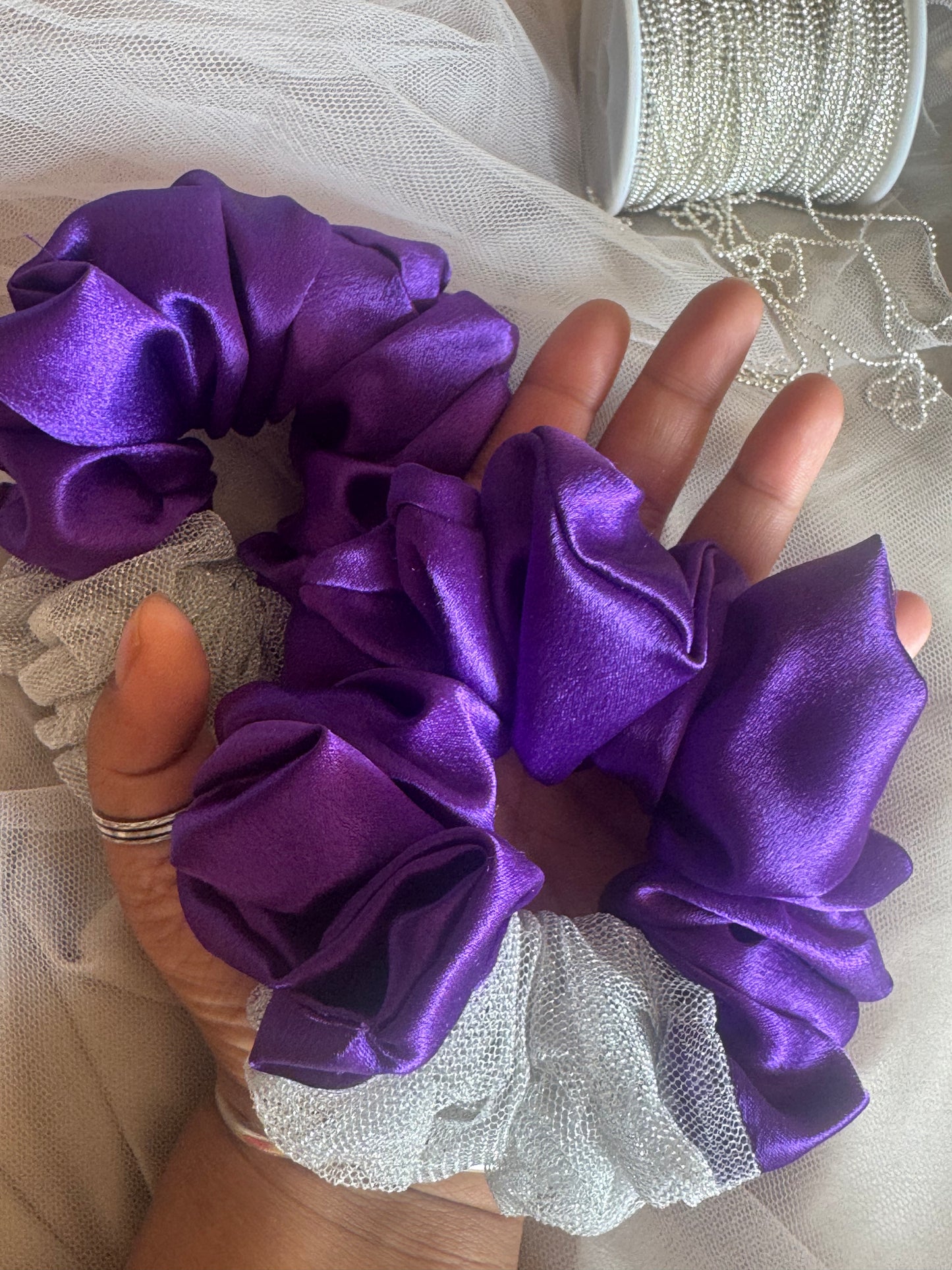 Two Purple Silver Snow Scrunchies - Front view of deep purple and shimmering silver satin and net scrunchies, ideal for adding volume and elegance to any hairstyle. Kept in a palm for size comparison.