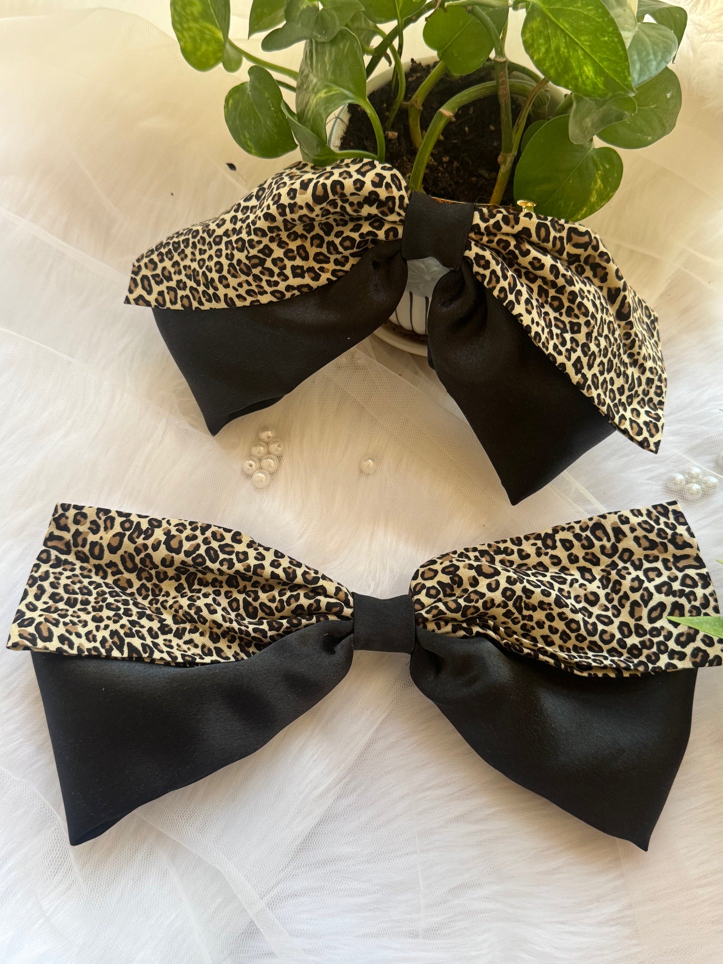 Two Kate Moss Hair Bows - Front view of oversized black satin and leopard print hair bow clips for bold, stylish looks with size comparison with a small pot