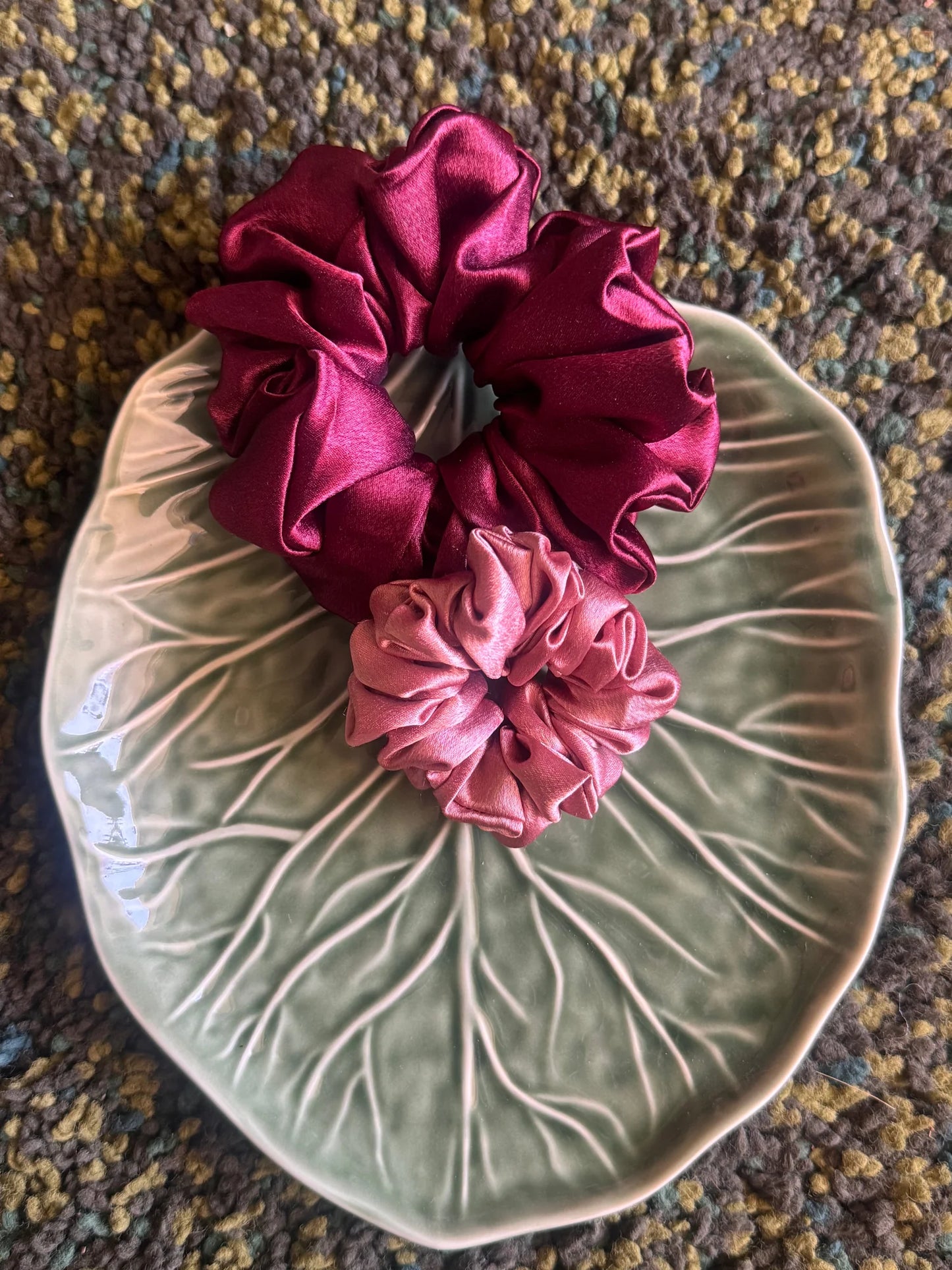 Dark fuchsia and light pink satin scrunchies duo by Bows and Bags India displayed on leaf-shaped ceramic dish, showcasing