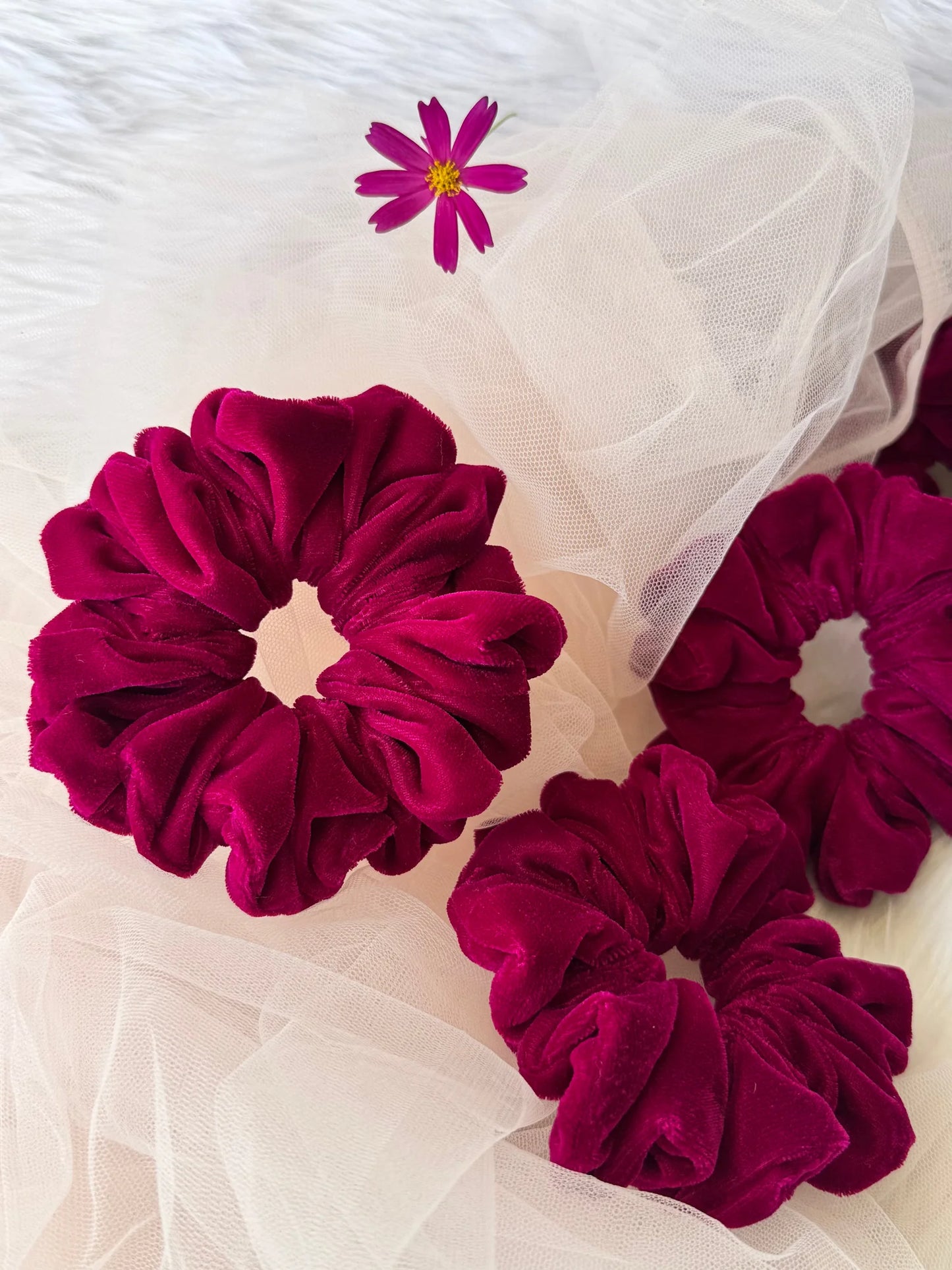 Hot pink velvet scrunchies by Bows and Bags India displayed on white tulle with small cosmos flower, handmade hair
