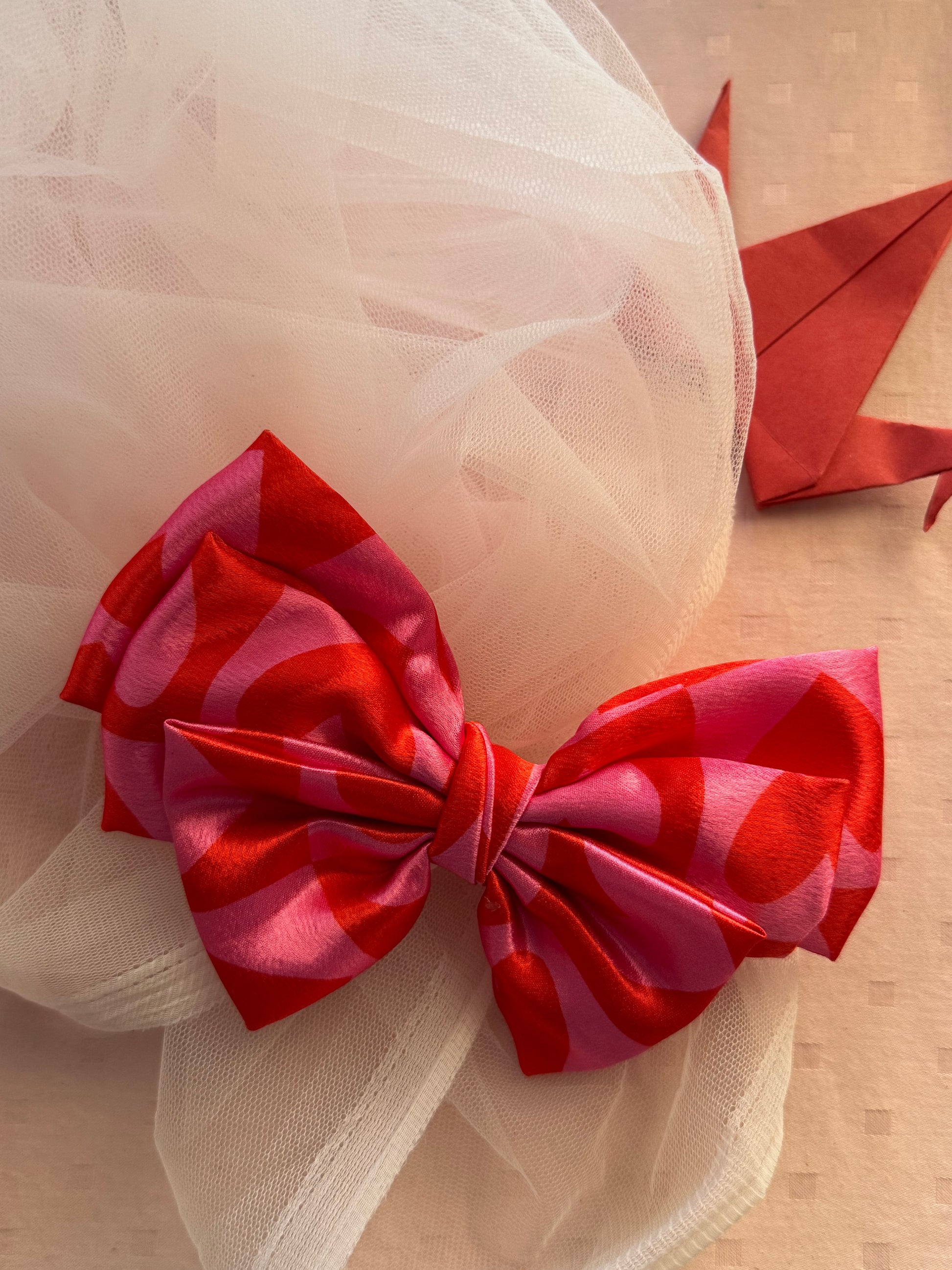 Love Struck Hair Bow Clip - Front view of a large pink satin hair bow with heart prints, radiating love and playfulness for a charming look