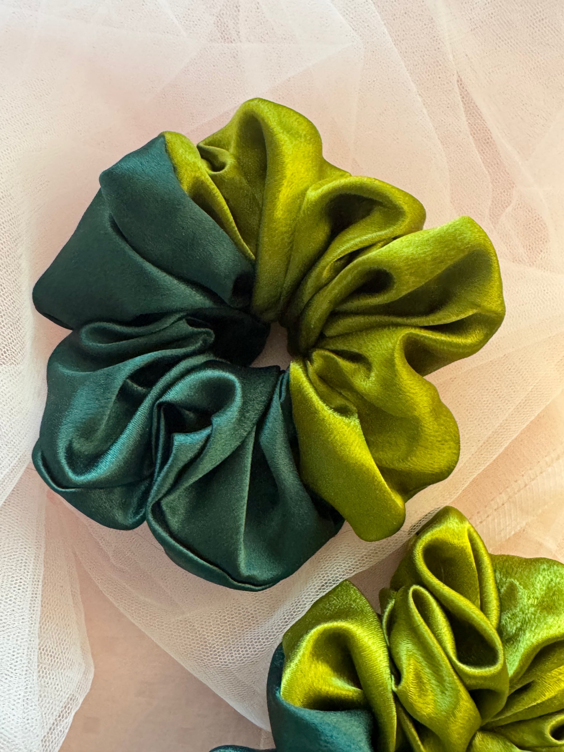 A luxurious olive and dark green dual-tone satin scrunchie for women, made from soft moss satin to reduce hair breakage, perfect for ponytails, buns, and stylish hair accessories.