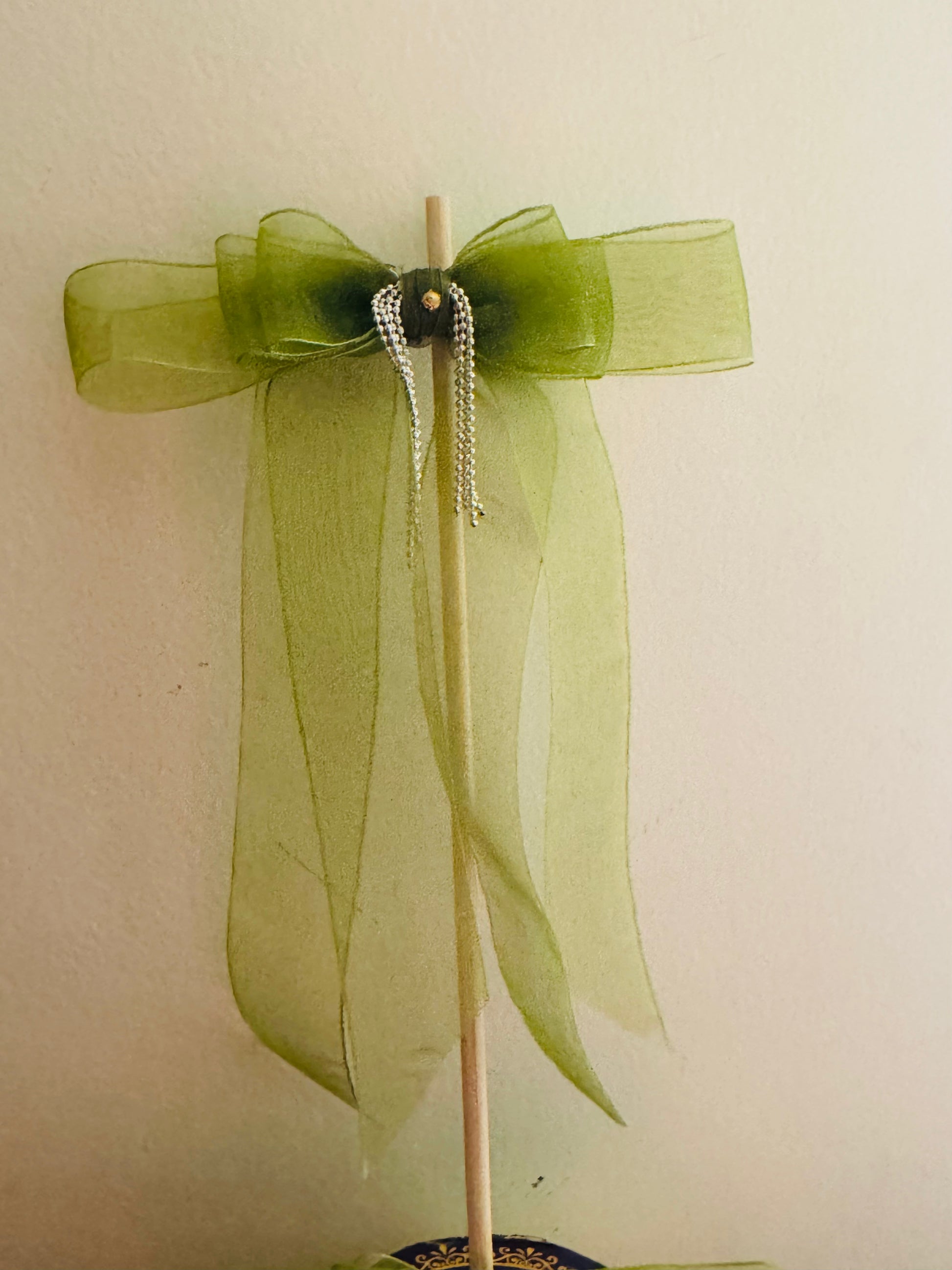 Tinker Bell Hair Bow Clip - Front view of a light green organza hair bow with a delicate silver chain detail for a graceful and elegant look. Mounted on a stick.