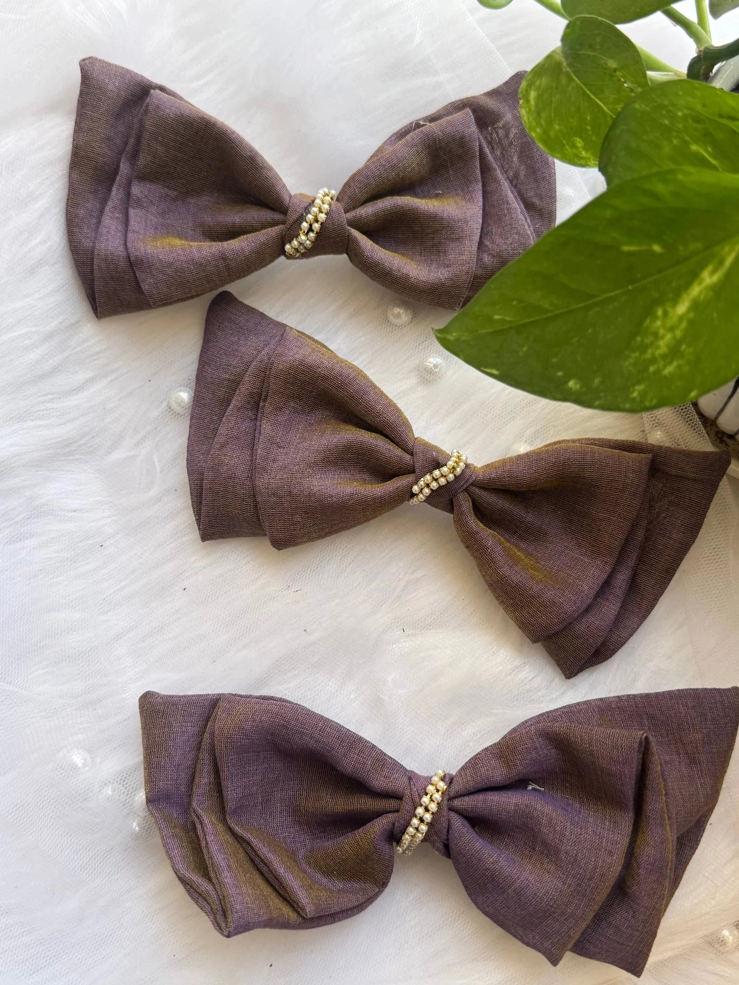 Three handmade dual-tone violet and brown cotton hair bows with pearl embellishments by Bows and Bags India, displayed on