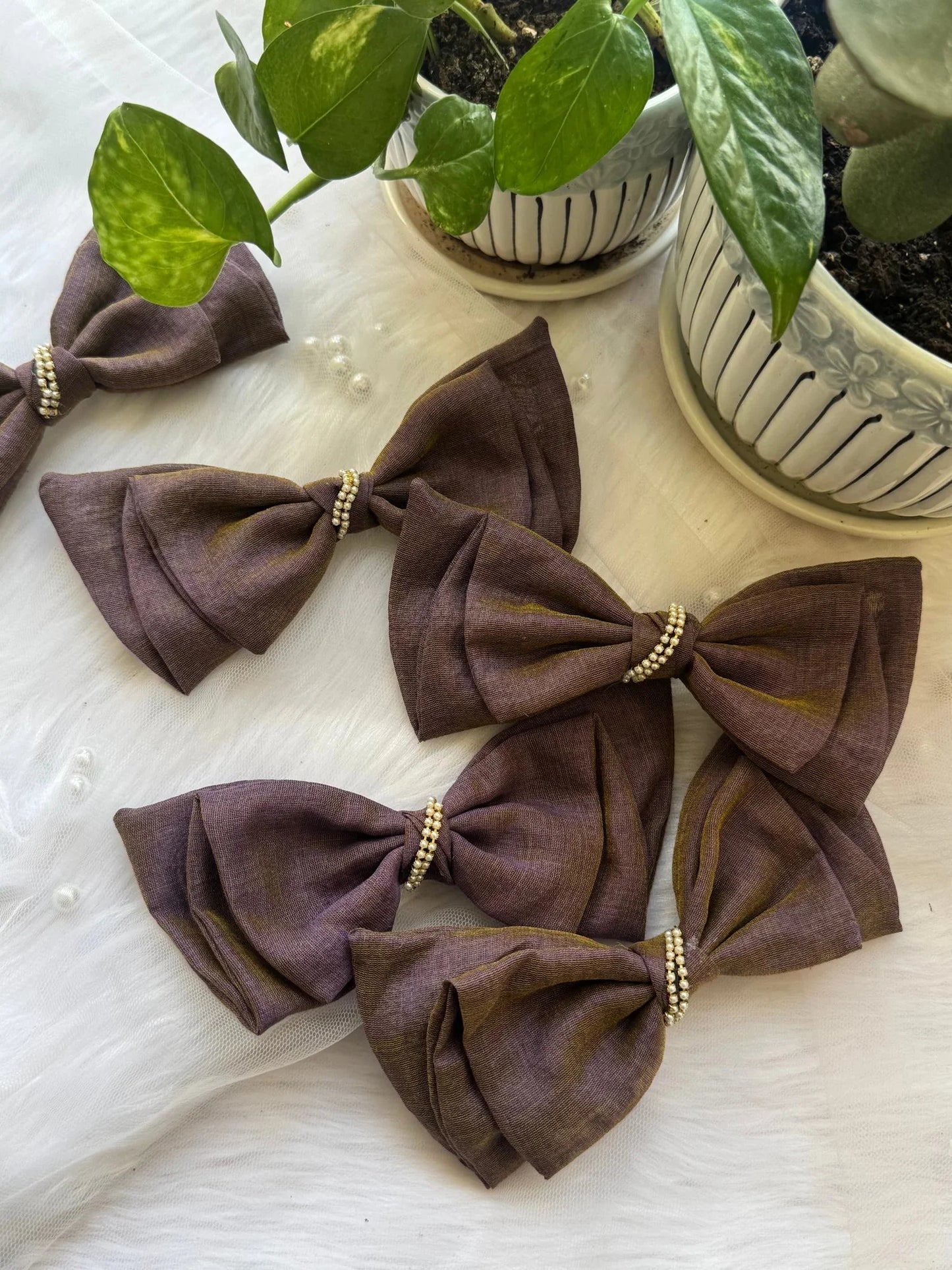 Flat lay of five handmade cotton dual-tone hair bow clips in blackcurrant violet and brown with pearl embellishments by Bows