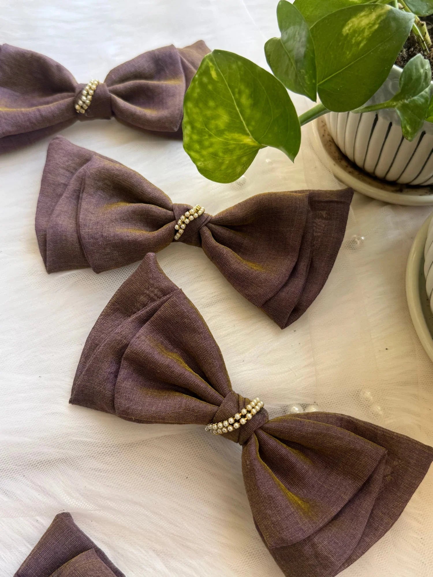 Blackcurrant Ice cotton hair bow with pearl embellishment displayed flat lay with potted plant, Bows and Bags India handmade