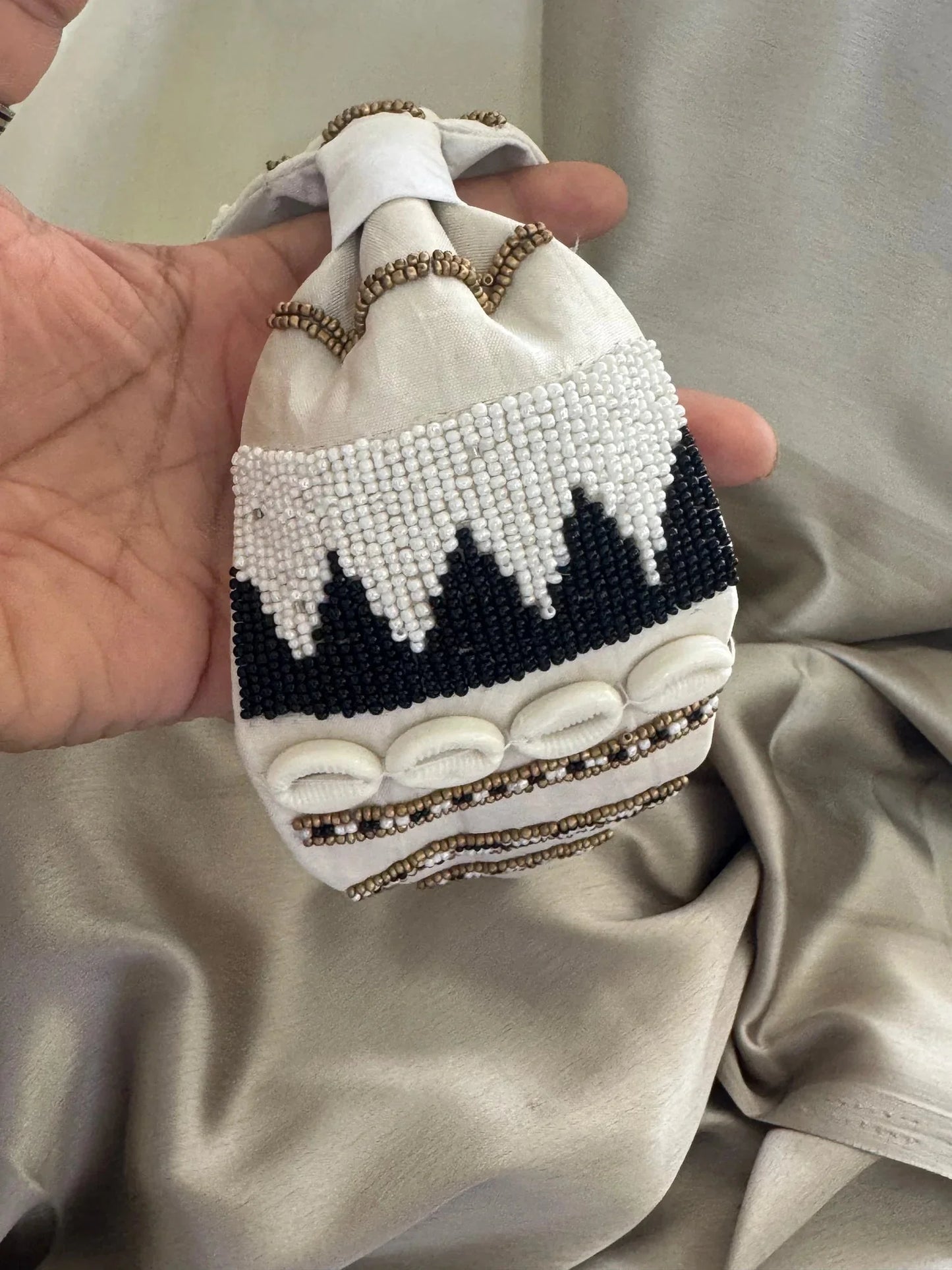 Handmade beaded satin headband by Bows and Bags India with white pearl and black beadwork detail held in hand, close-up view