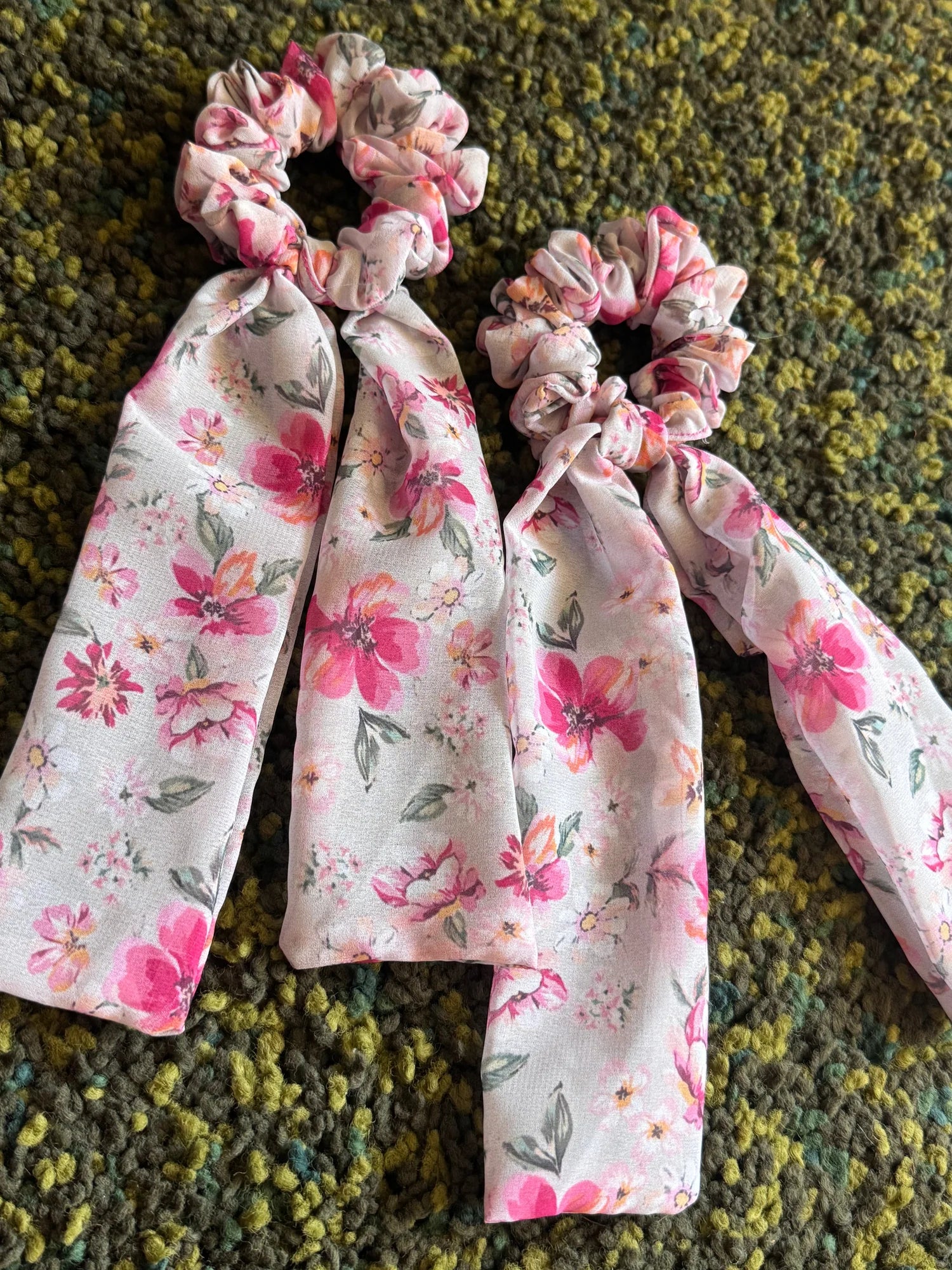 Floral pink georgette tail scrunchie with delicate tails displayed on textured fabric by Bows and Bags India