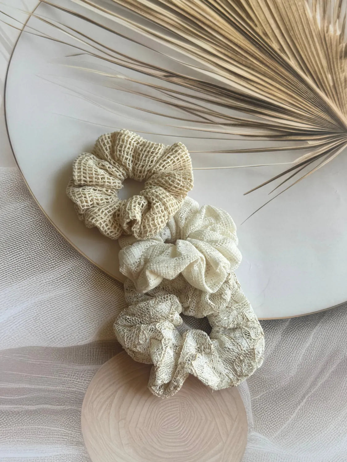 Three cream net mesh handmade scrunchies from Bows and Bags India displayed on wooden surface with dried grasses