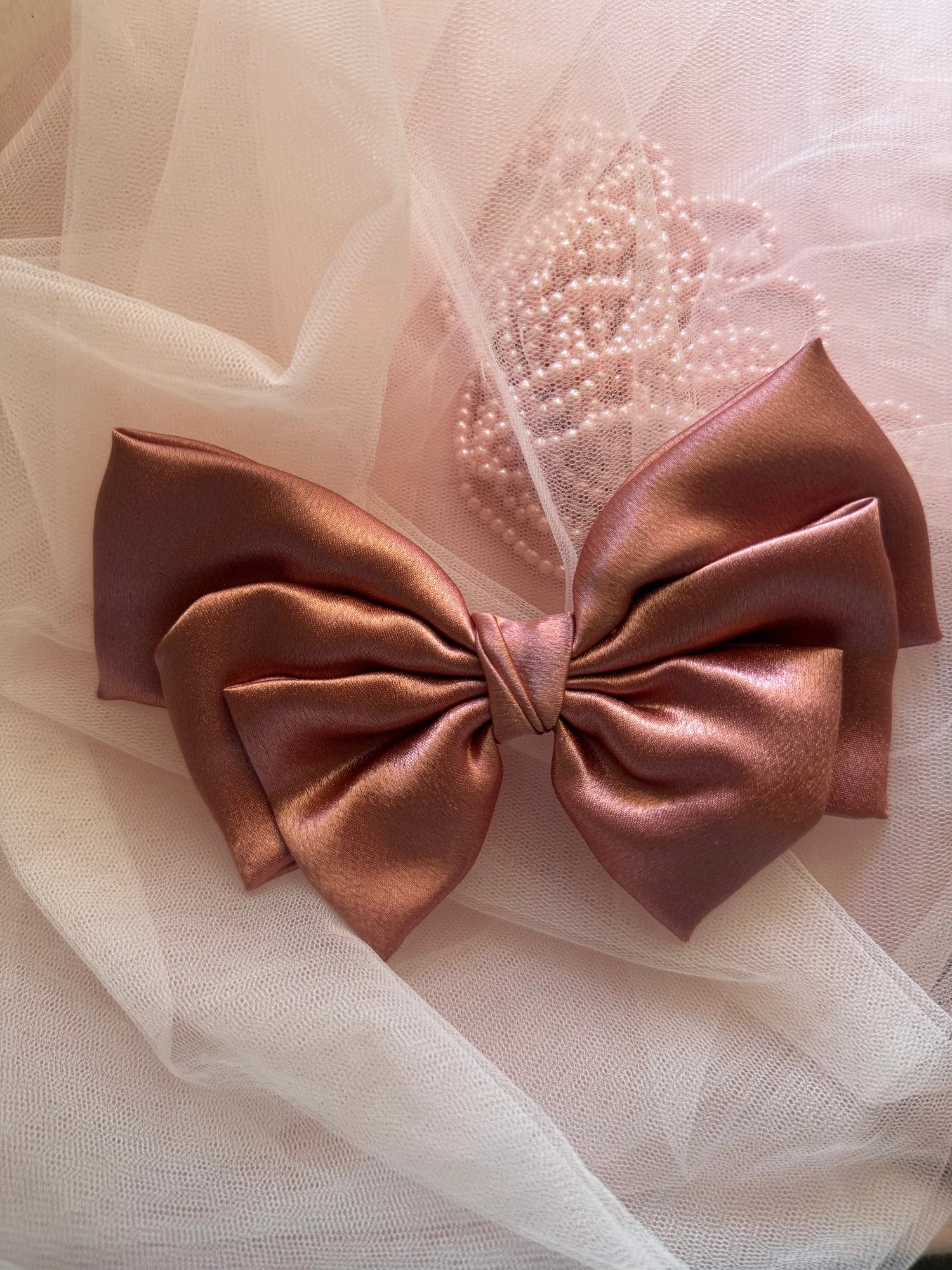 Metallic peach satin hair bow detail with pearl beading on tulle backdrop by Bows and Bags India