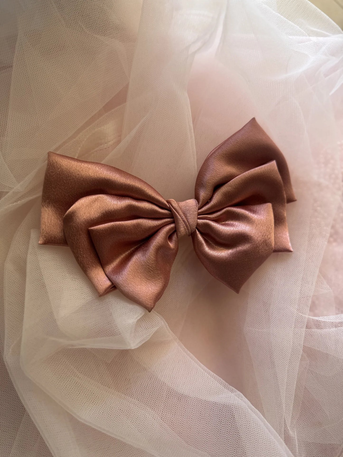 Metallic peach satin hair bow by Bows and Bags India displayed on sheer tulle fabric, showcasing luxurious handmade bow