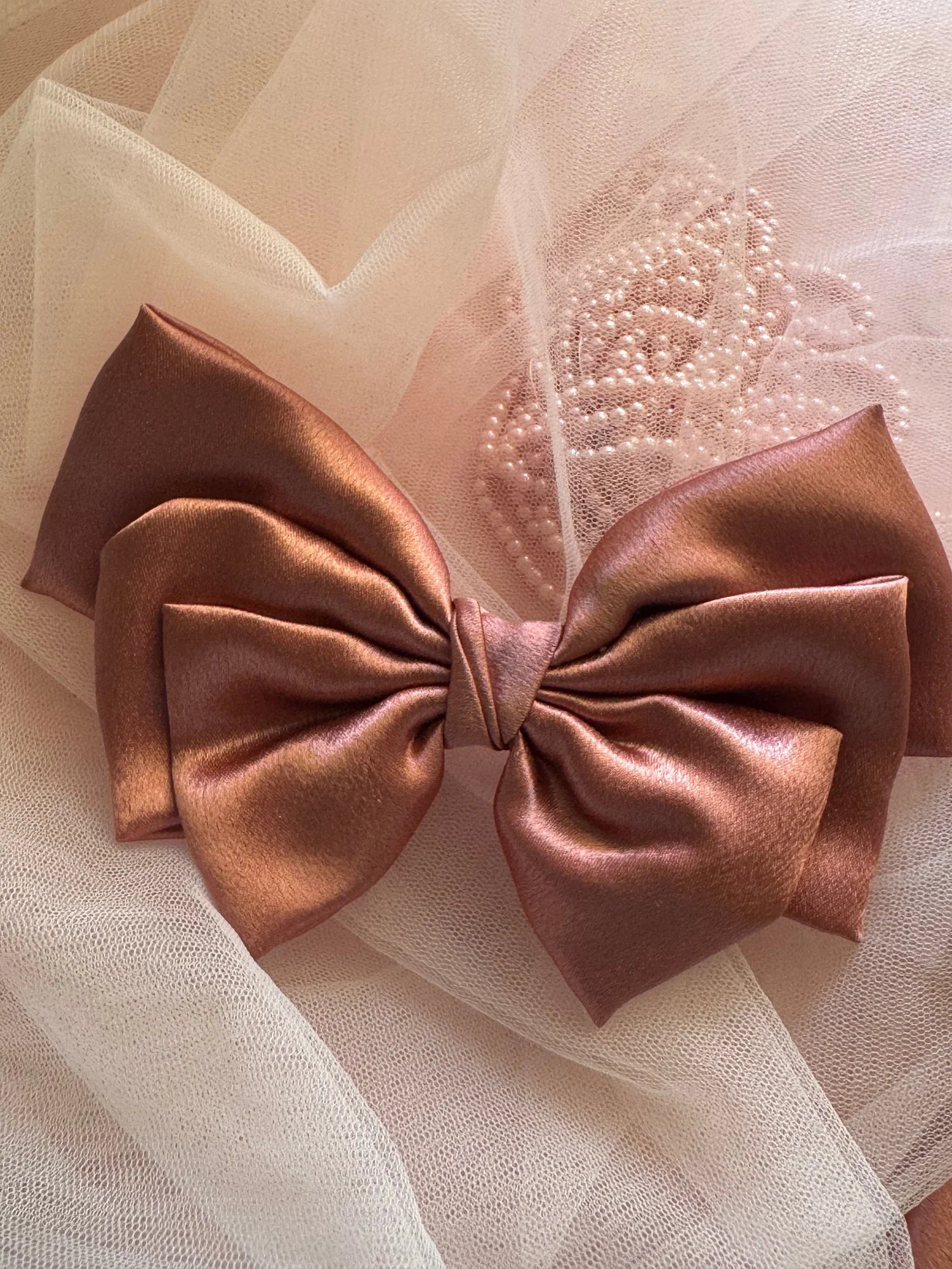 Metallic peach satin hair bow by Bows and Bags India with pearl beaded detail on blush tulle backdrop, handmade accessory