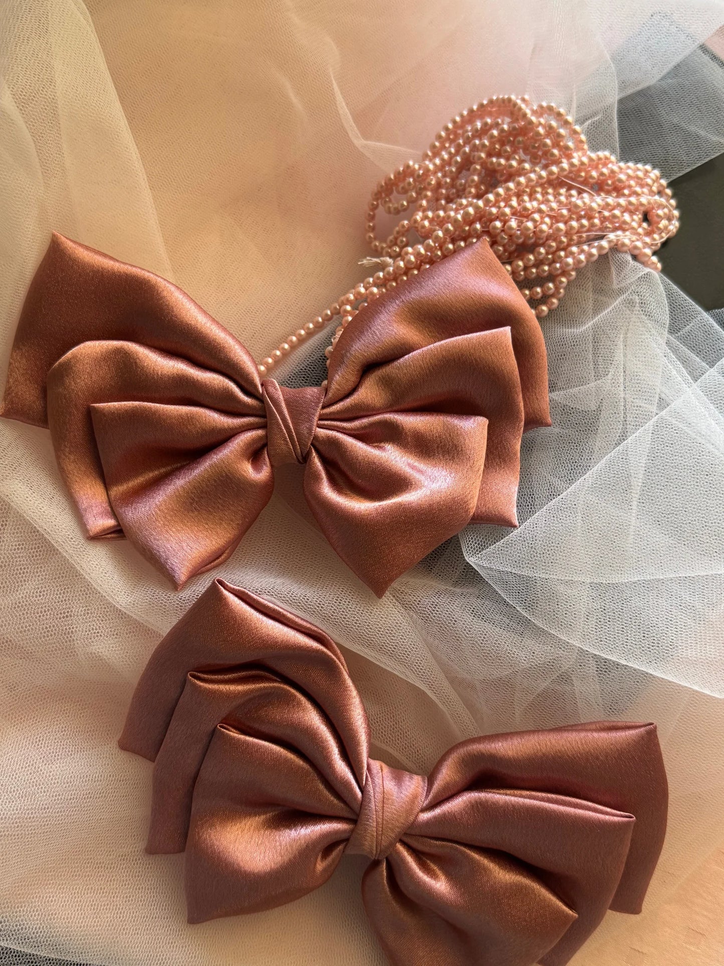 Metallic peach satin hair bow with pearl beaded detail by Bows and Bags India, handmade accessory styled with tulle fabric