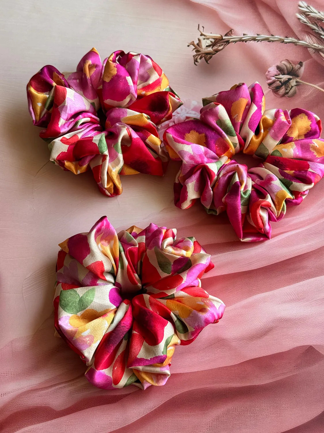 Garden Bloom floral print XL satin scrunchies in magenta and gold displayed flat on pink fabric by Bows and Bags India