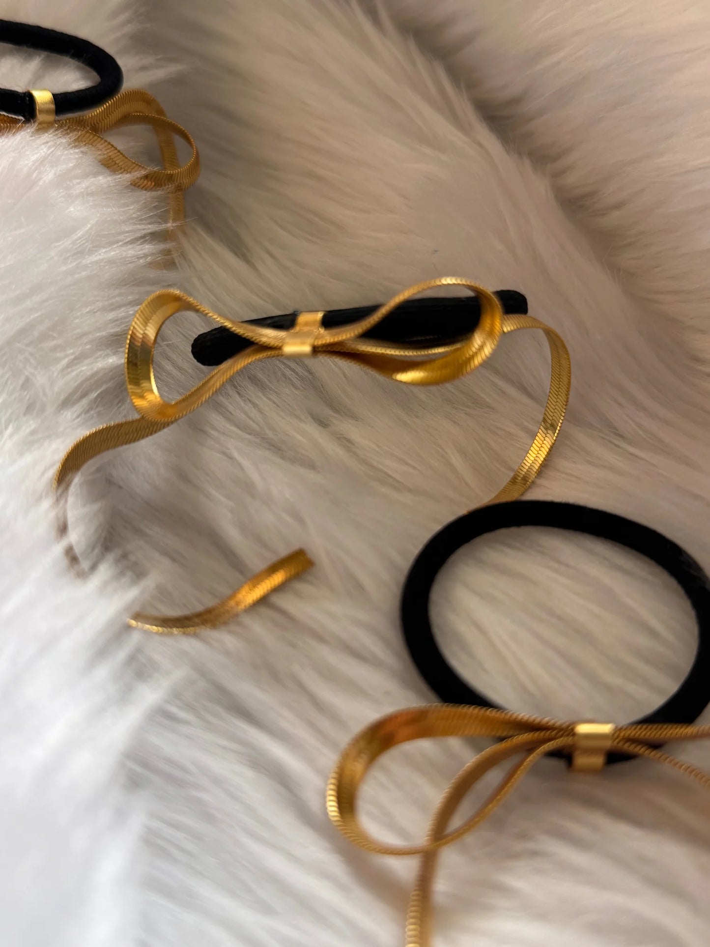 Golden chain bow metal rubber bands with black elastic displayed on white fur, Bows and Bags India handmade hair accessories