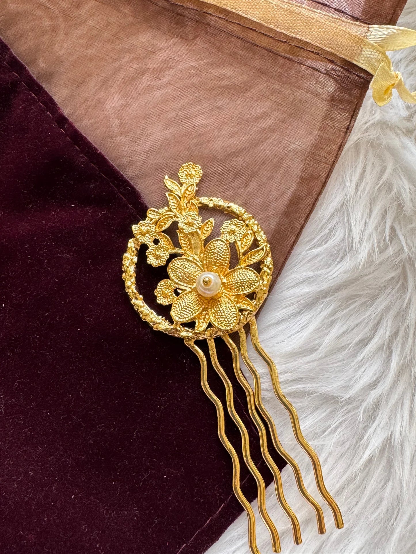 Golden Flora handmade hair pin with textured gold flowers and pearl center, displayed on burgundy velvet by Bows and Bags