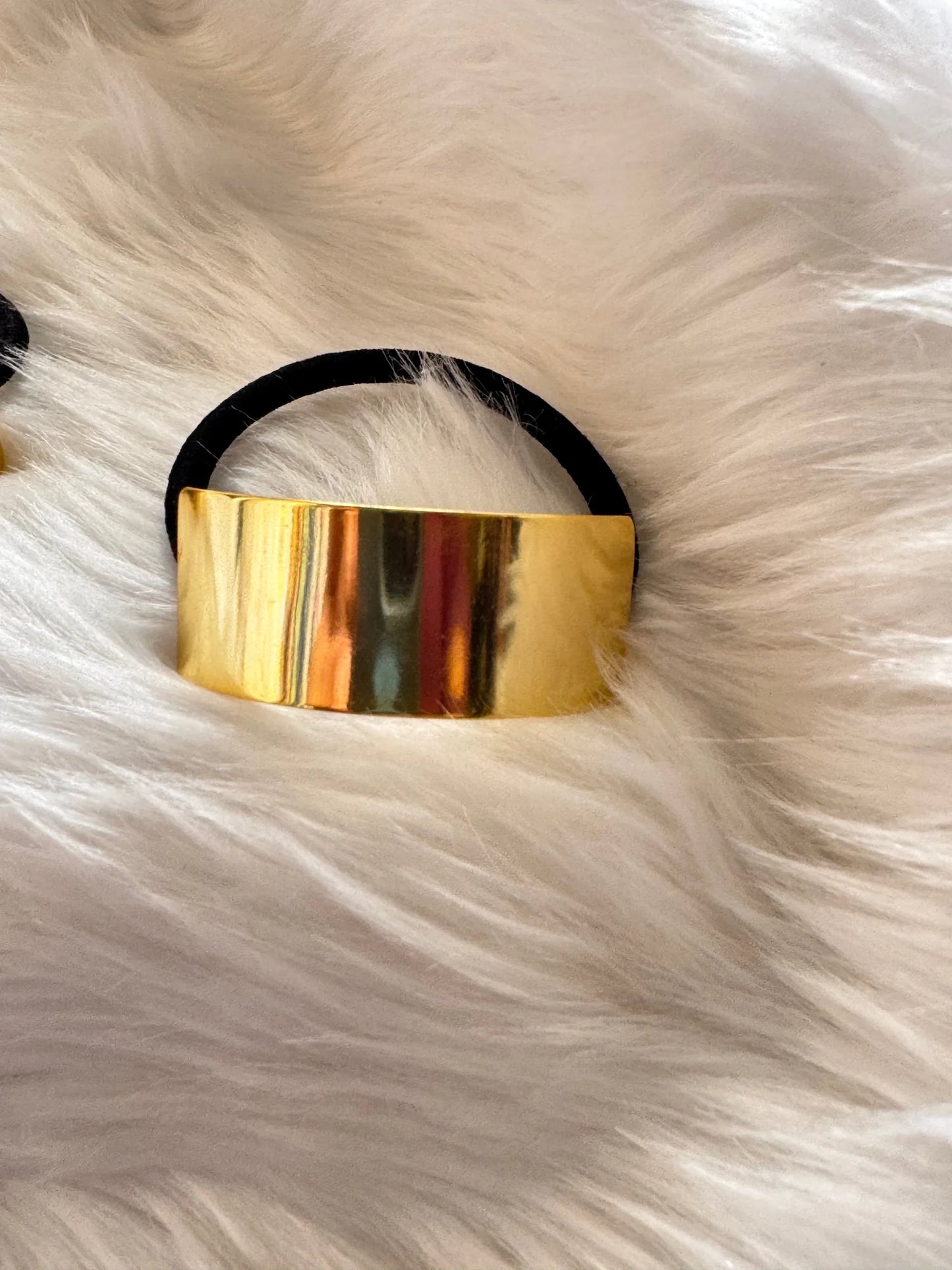 Golden metal bar hair tie with black elastic band on cream fur background by Bows and Bags India