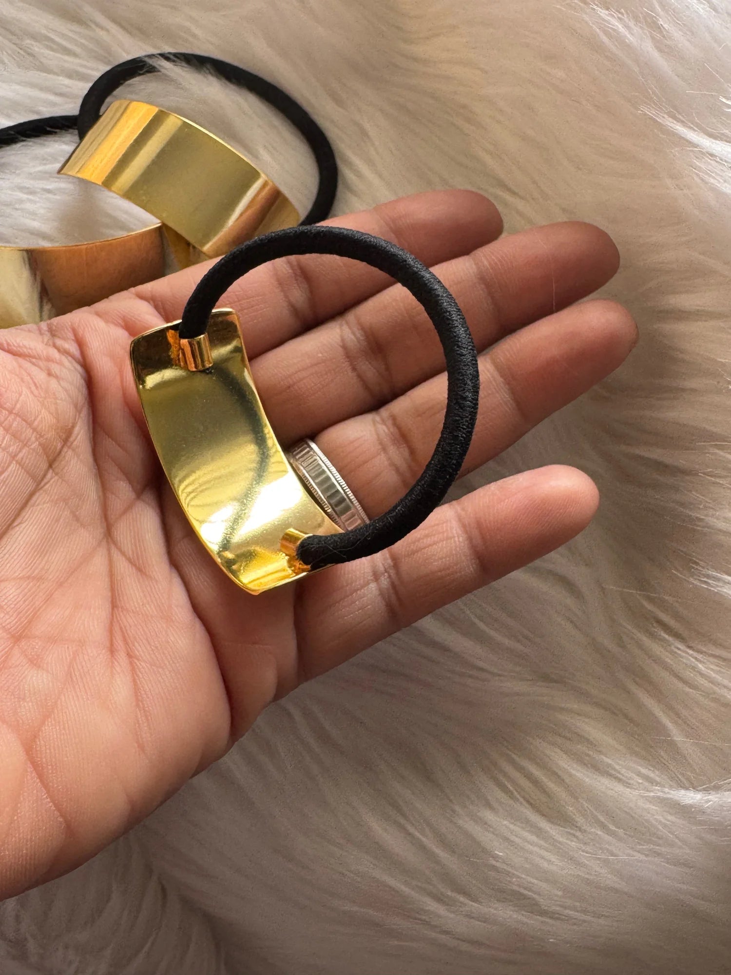 Golden metal bar hair tie with black elastic band held in hand, showcasing geometric cuff design by Bows and Bags India