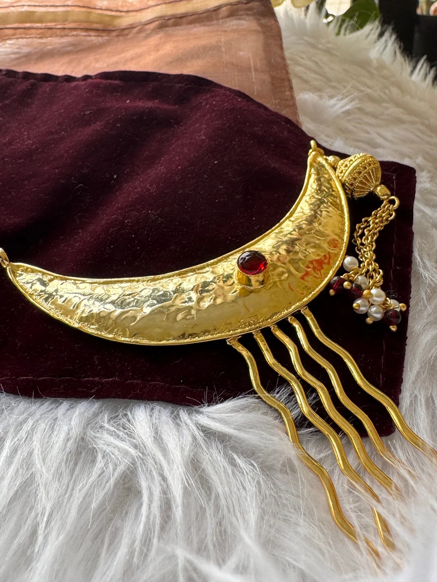 Golden Moon hair pin with hammered gold crescent, red stone, and pearl dangles on maroon velvet by Bows and Bags India