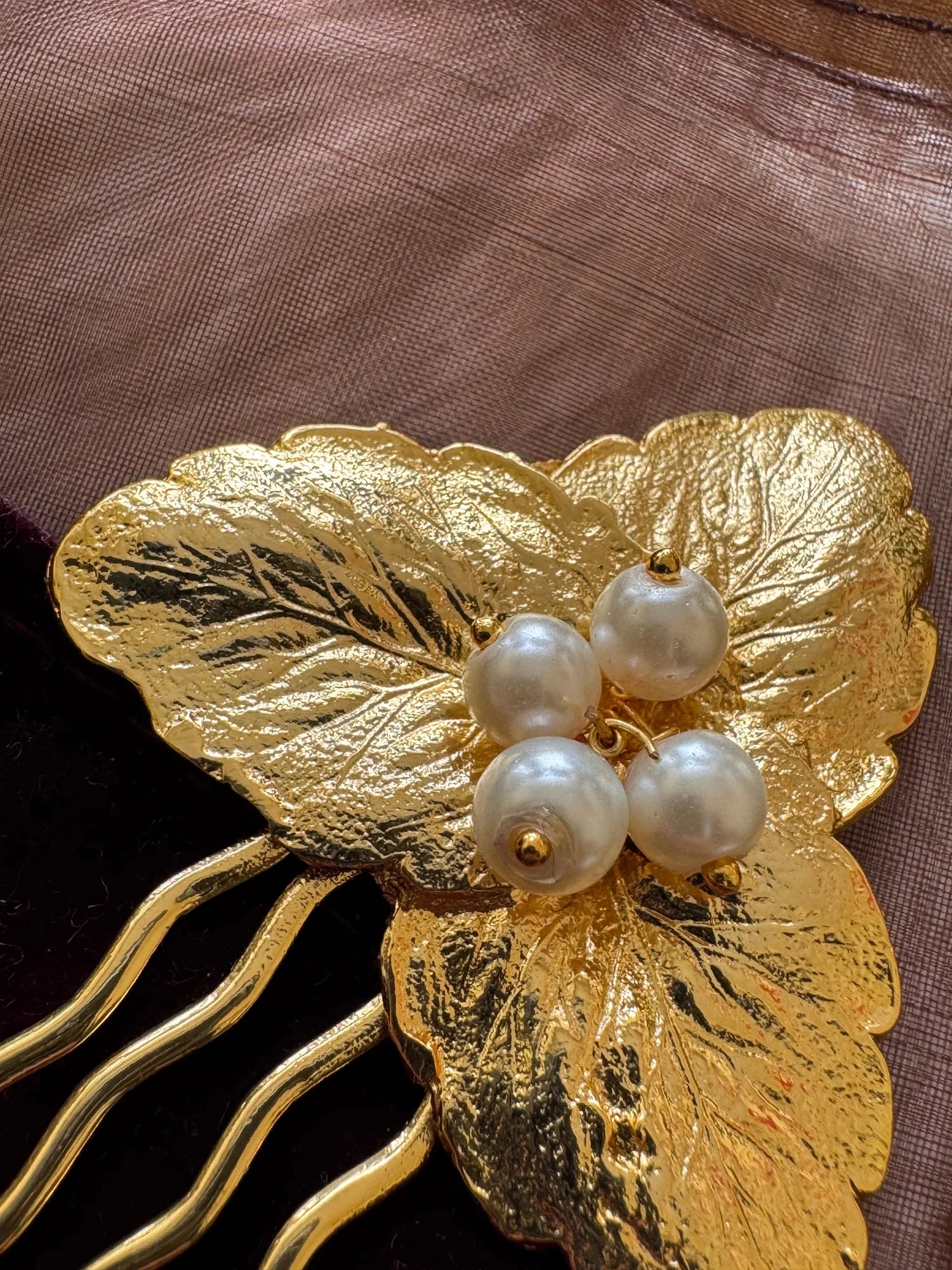 Golden textured leaf hair pin with pearl cluster detail by Bows and Bags India, close-up view on fabric