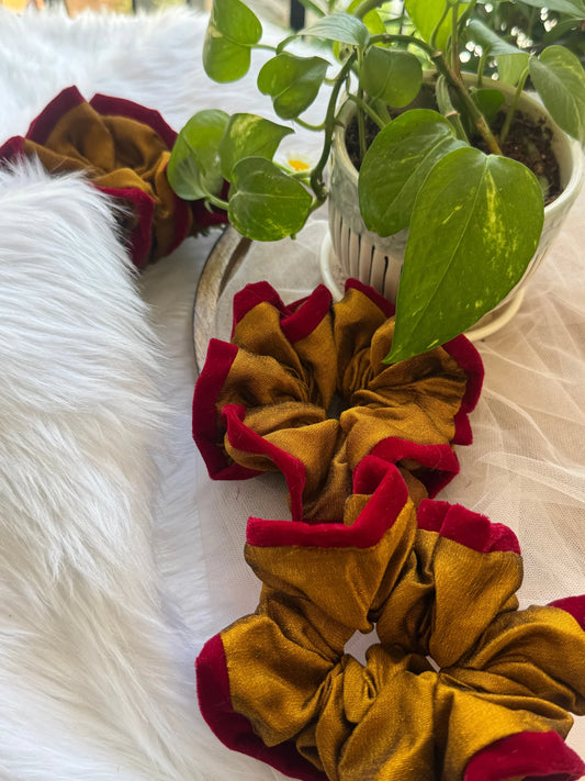 Golden yellow silk scrunchie with maroon velvet trim by Bows and Bags India, displayed with green plants and white fur