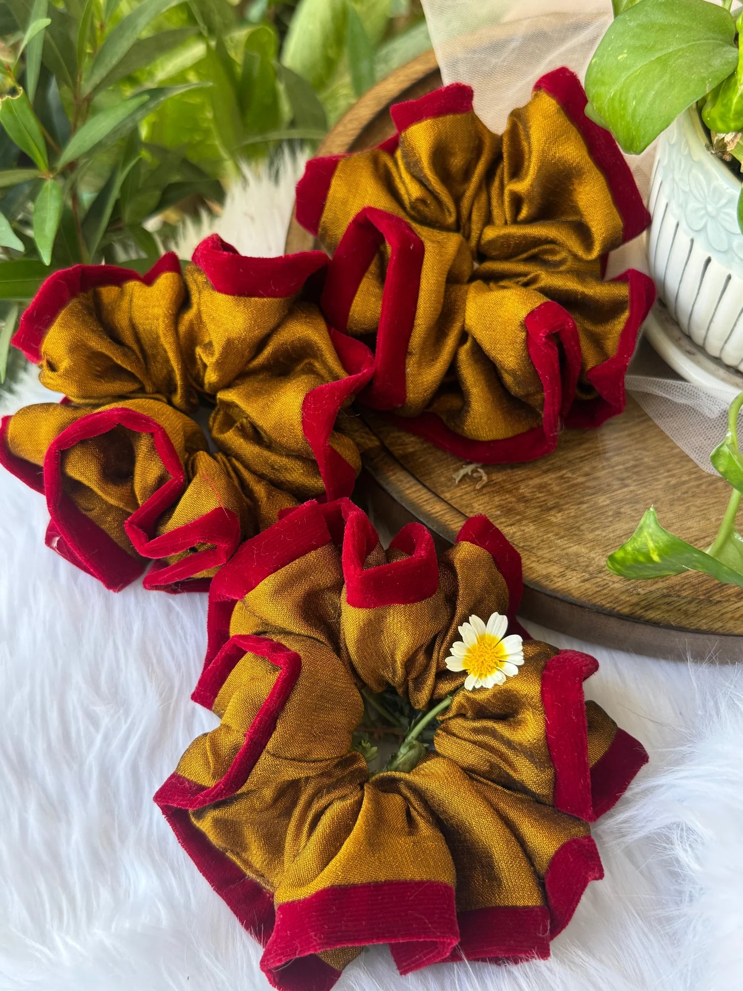 Golden yellow and maroon silk scrunchies by Bows and Bags India displayed on wooden surface with white fabric and fresh