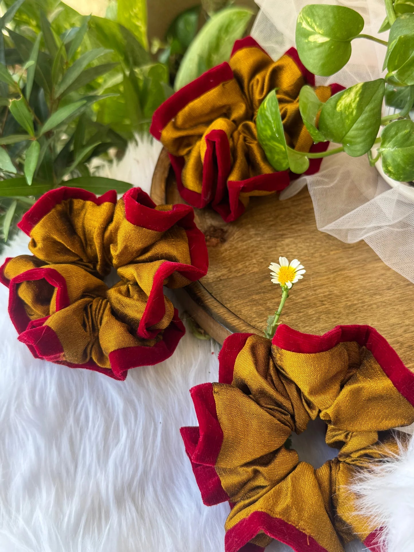Golden yellow silk scrunchie with maroon velvet trim by Bows and Bags India, displayed on wooden surface with green plants