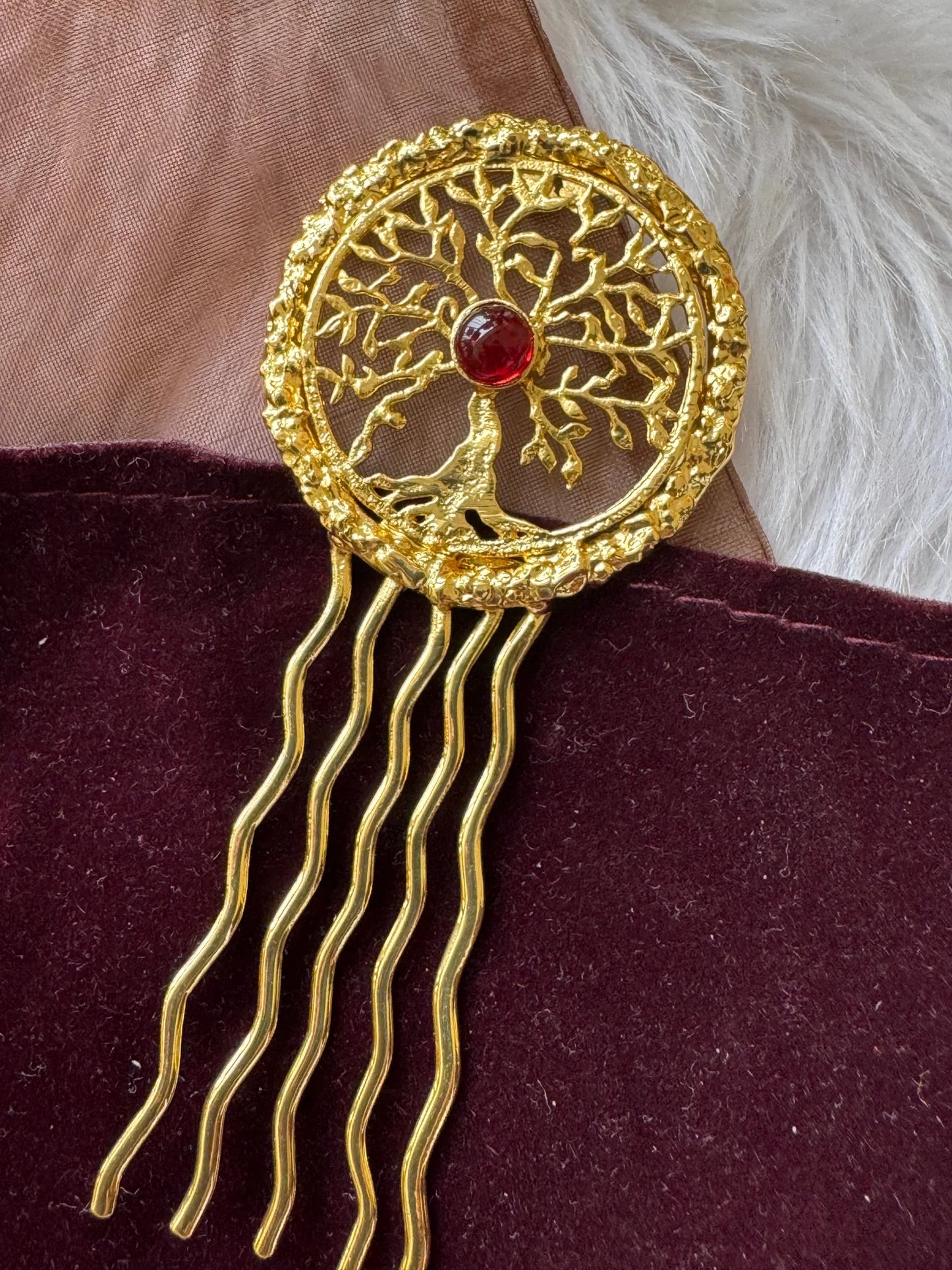 Golden Tree hair pin with intricate tree of life design, red stone center, and wavy gold prongs on burgundy velvet by Bows