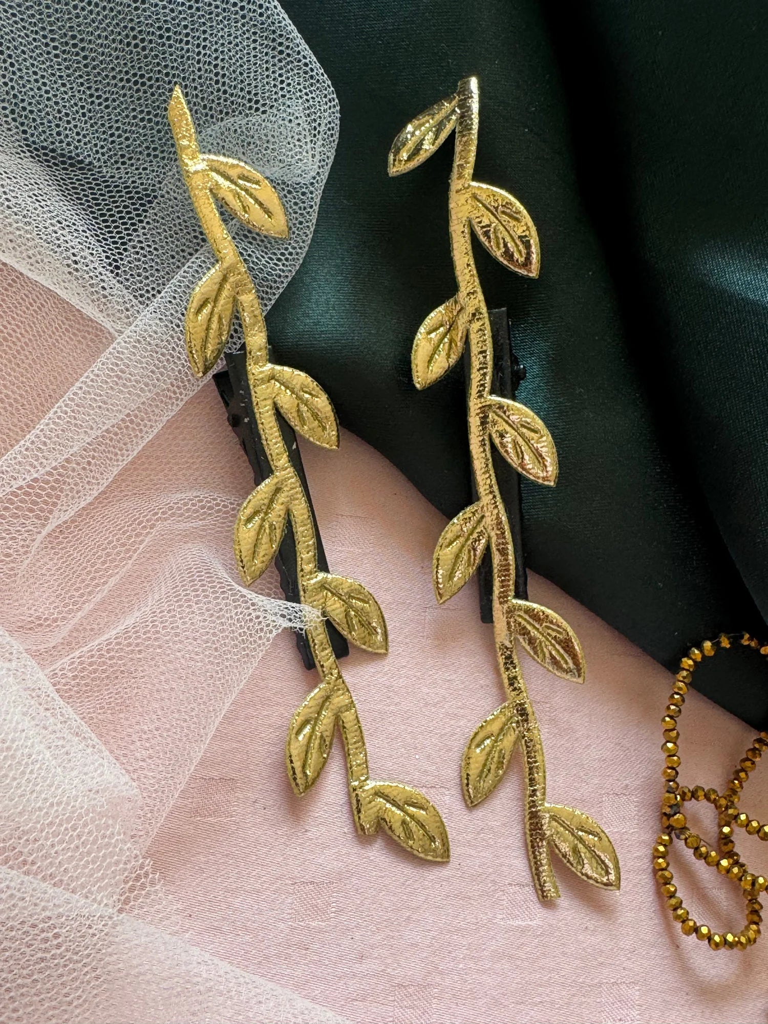 Golden Twig handmade hair clips in gold with leaf details on pink and green fabric, Bows and Bags India