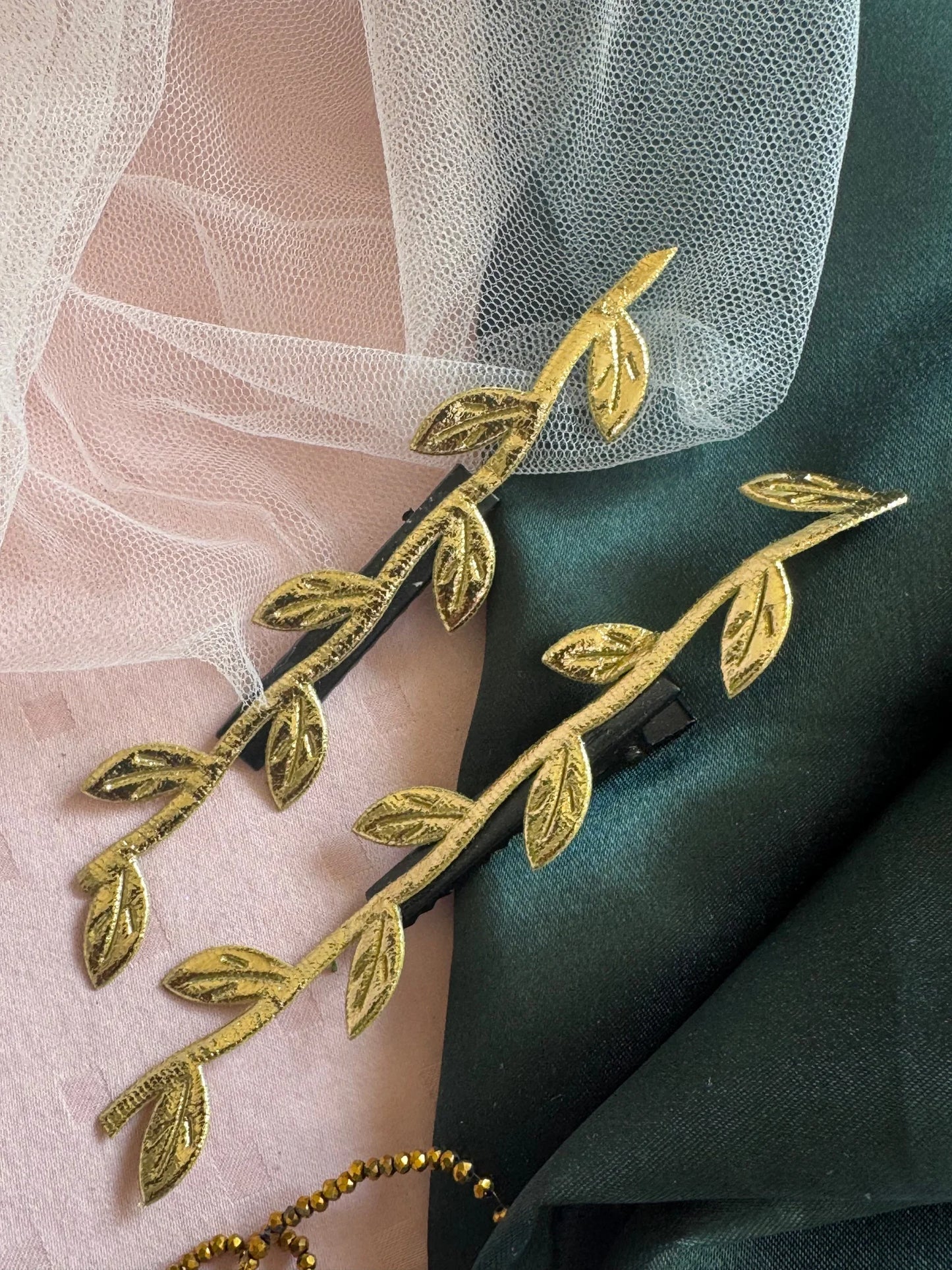 Golden Twig handmade hair clips in gold with leaf details on pink and green fabric by Bows and Bags India