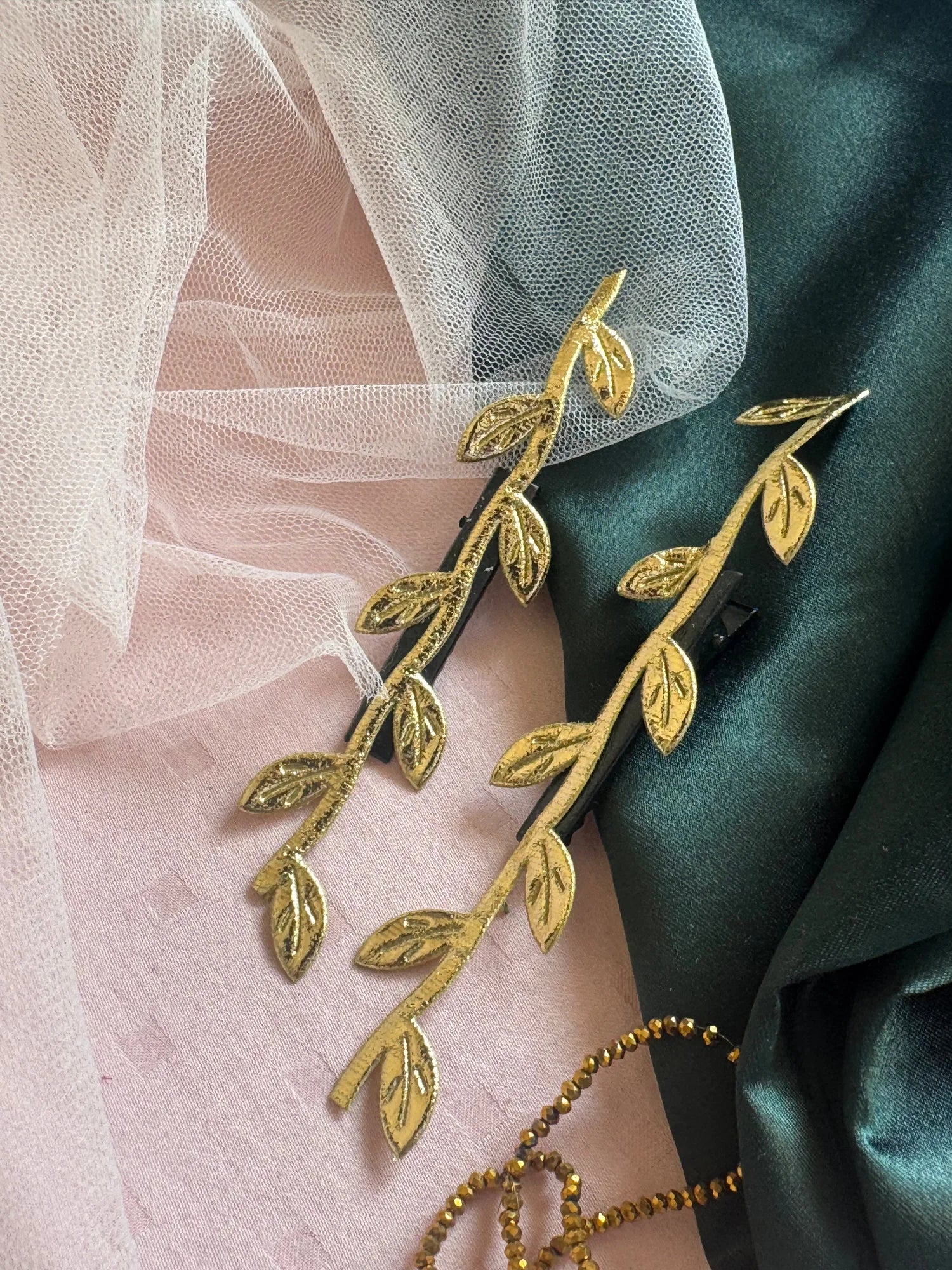 Golden Twig handmade hair clips in gold with leaf details on pink and teal fabrics by Bows and Bags India