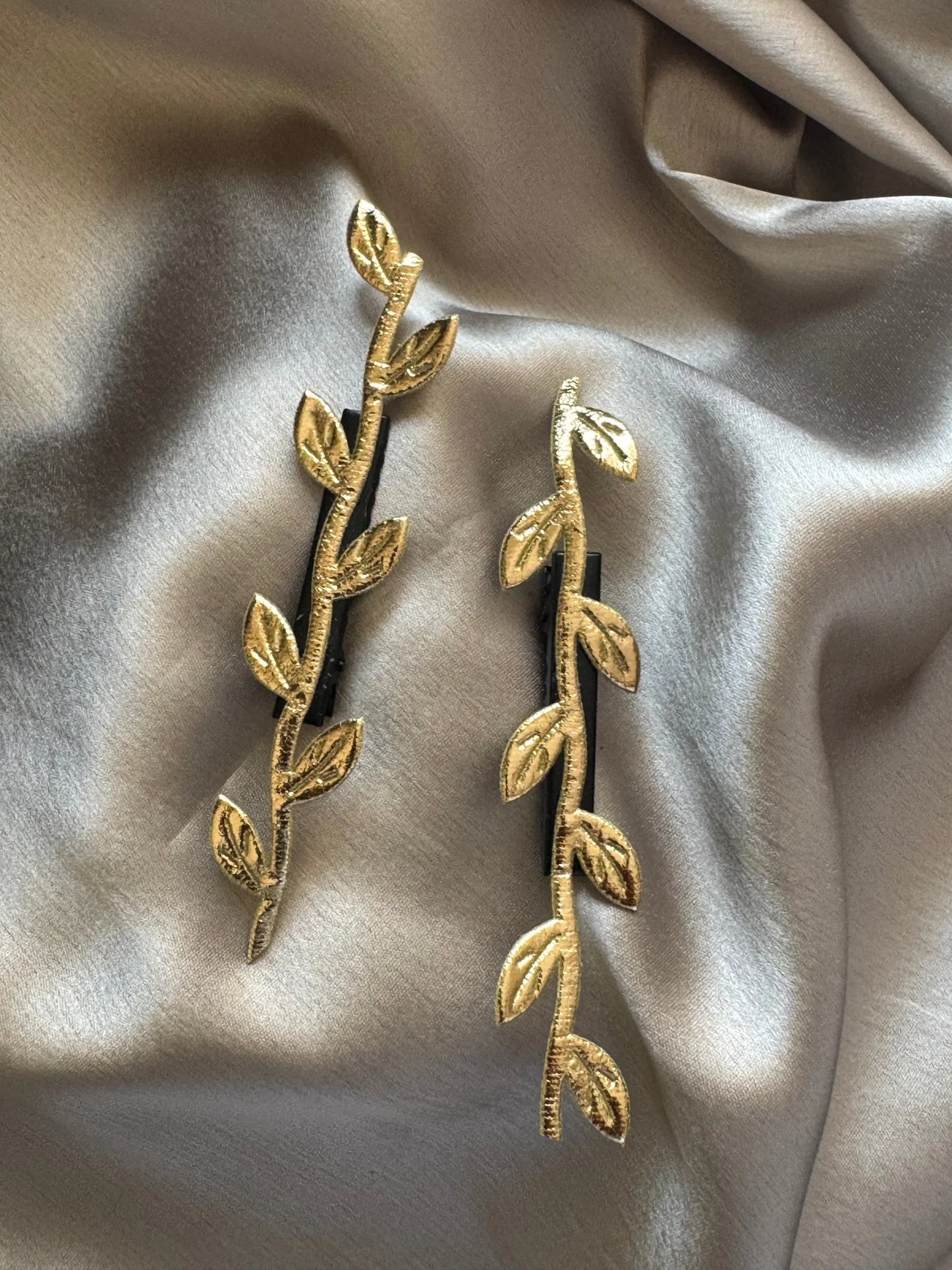 Golden Twig hair clip pair by Bows and Bags India with textured leaf details on cream fabric backdrop