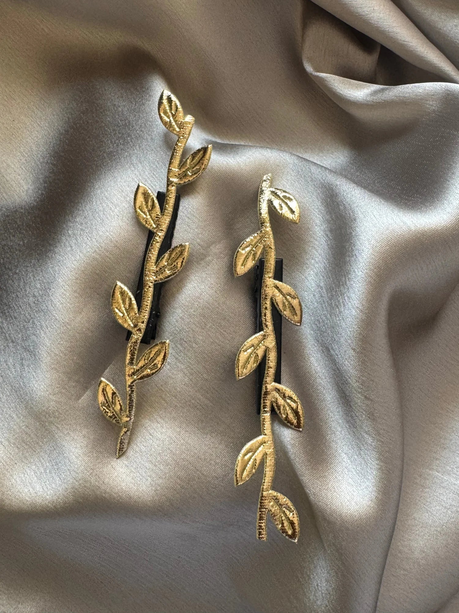 Golden Twig handmade hair clips by Bows and Bags India with leaf details on cream fabric backdrop