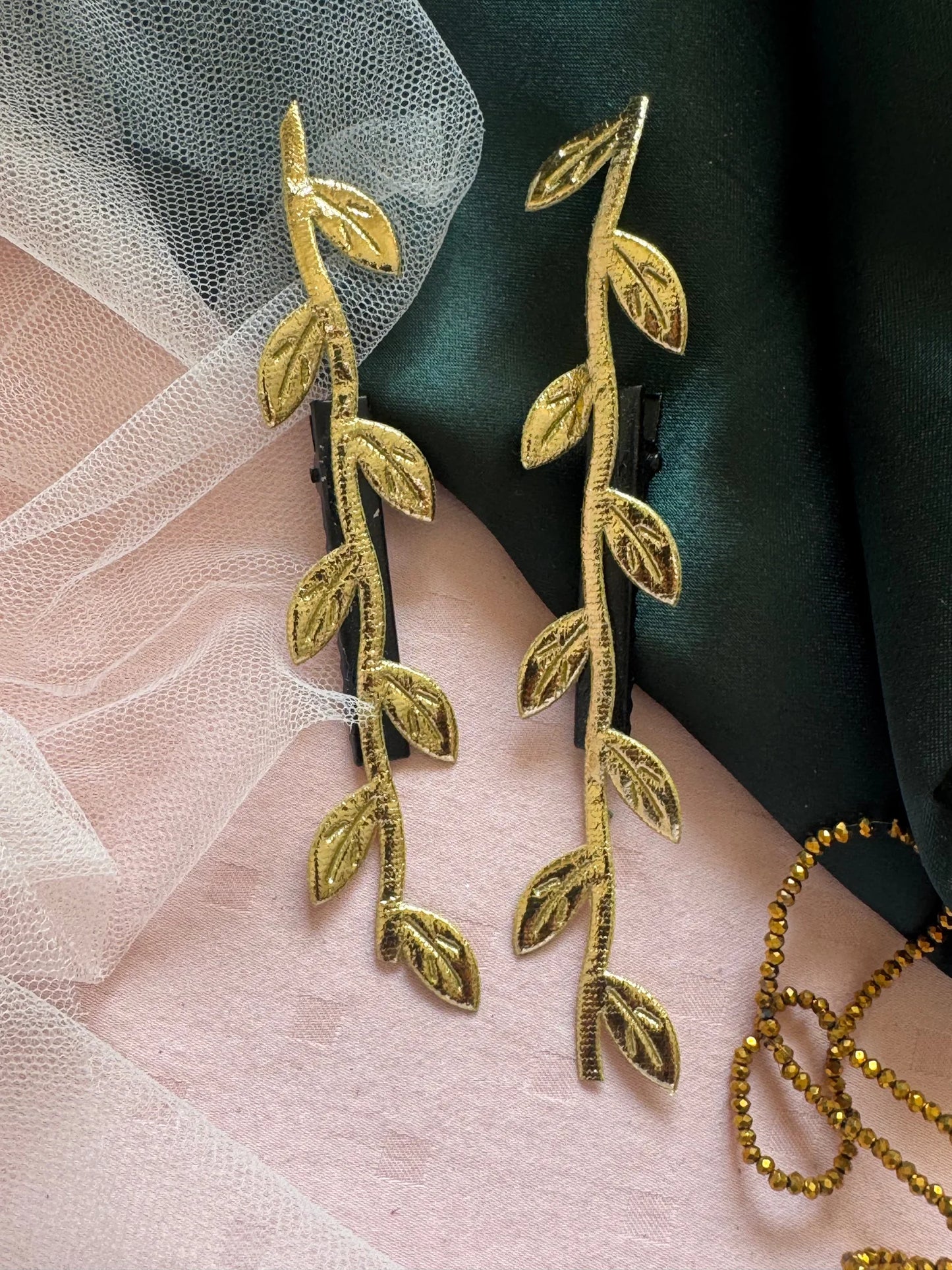 Golden Twig handmade hair clip with leaf details on pink and green fabric, lifestyle shot by Bows and Bags India