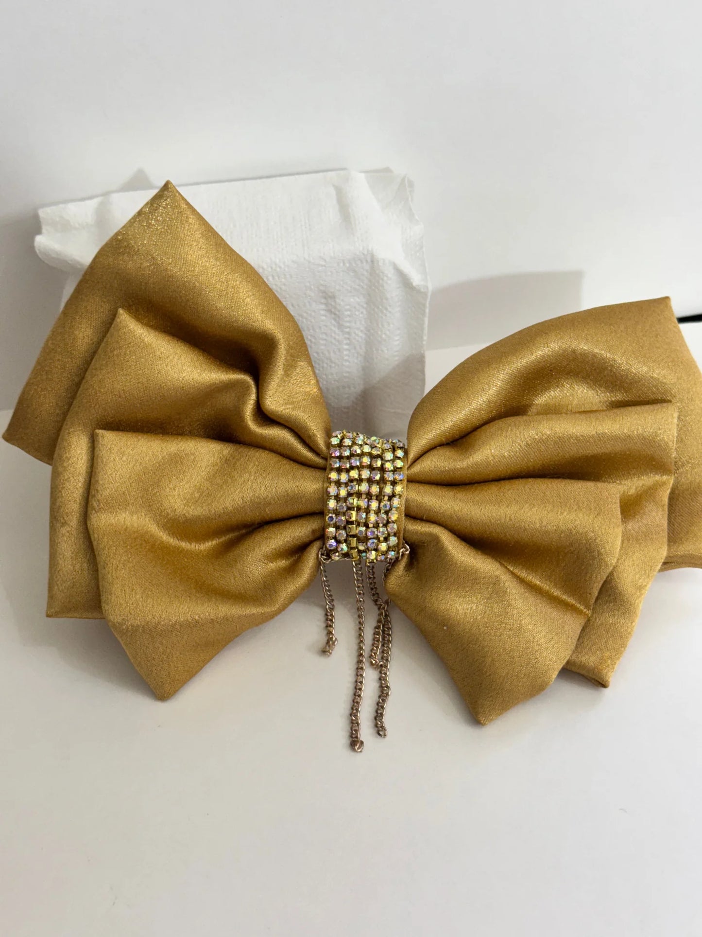 Golden satin hair bow with stone and chain embellishments by Bows and Bags India, displayed on white tissue with detailed
