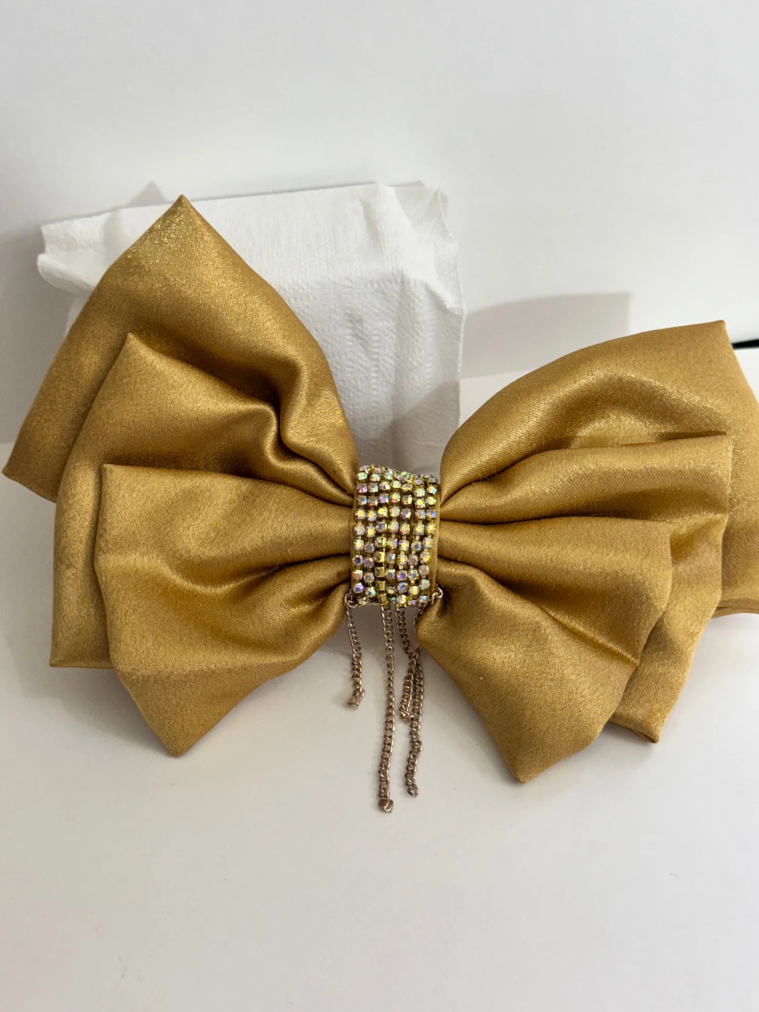 Golden satin hair bow with stone and chain embellishments by Bows and Bags India, displayed on white tissue with detailed
