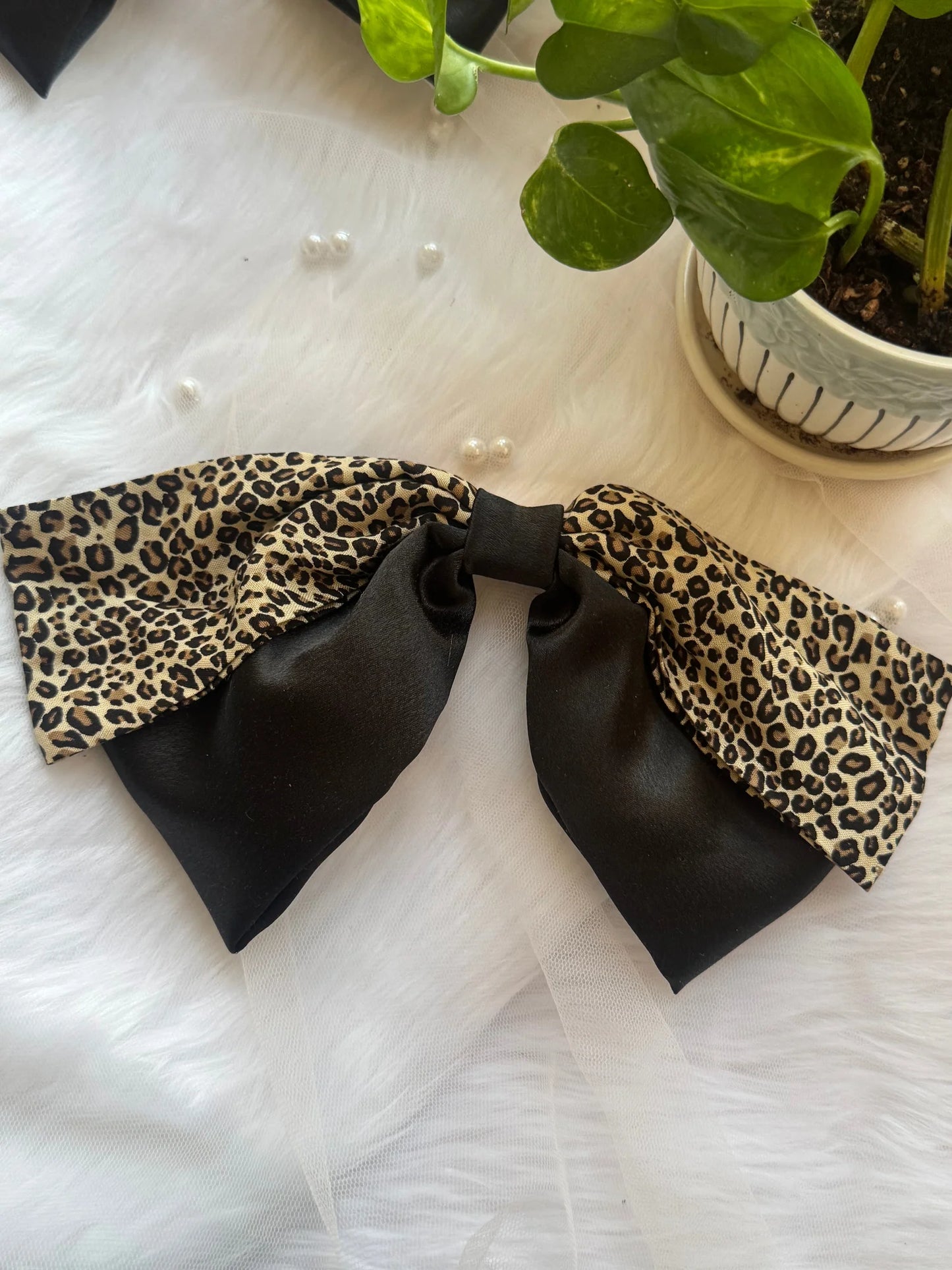 Kate Moss handmade hair bow with black satin and leopard print design by Bows and Bags India on white textured background