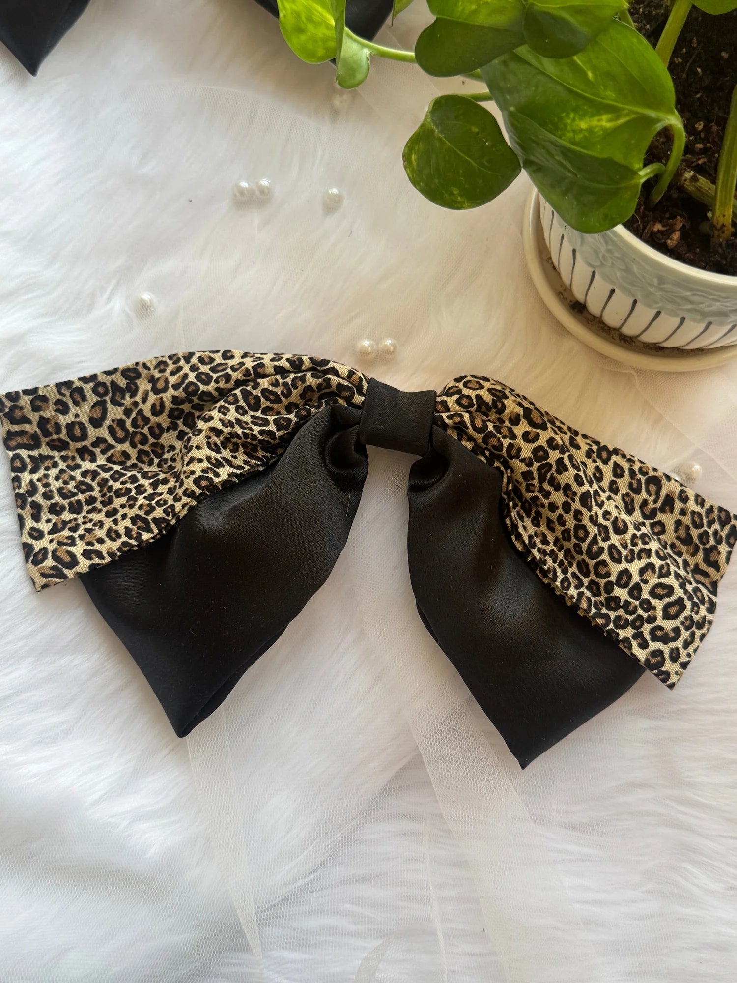 Kate Moss handmade hair bow with black satin and leopard print design by Bows and Bags India on white textured background