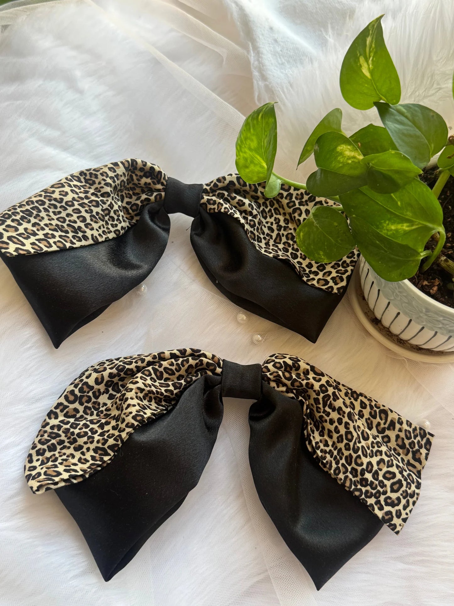 Two handmade Kate Moss hair bows with black satin and leopard print detail from Bows and Bags India, displayed flat lay style