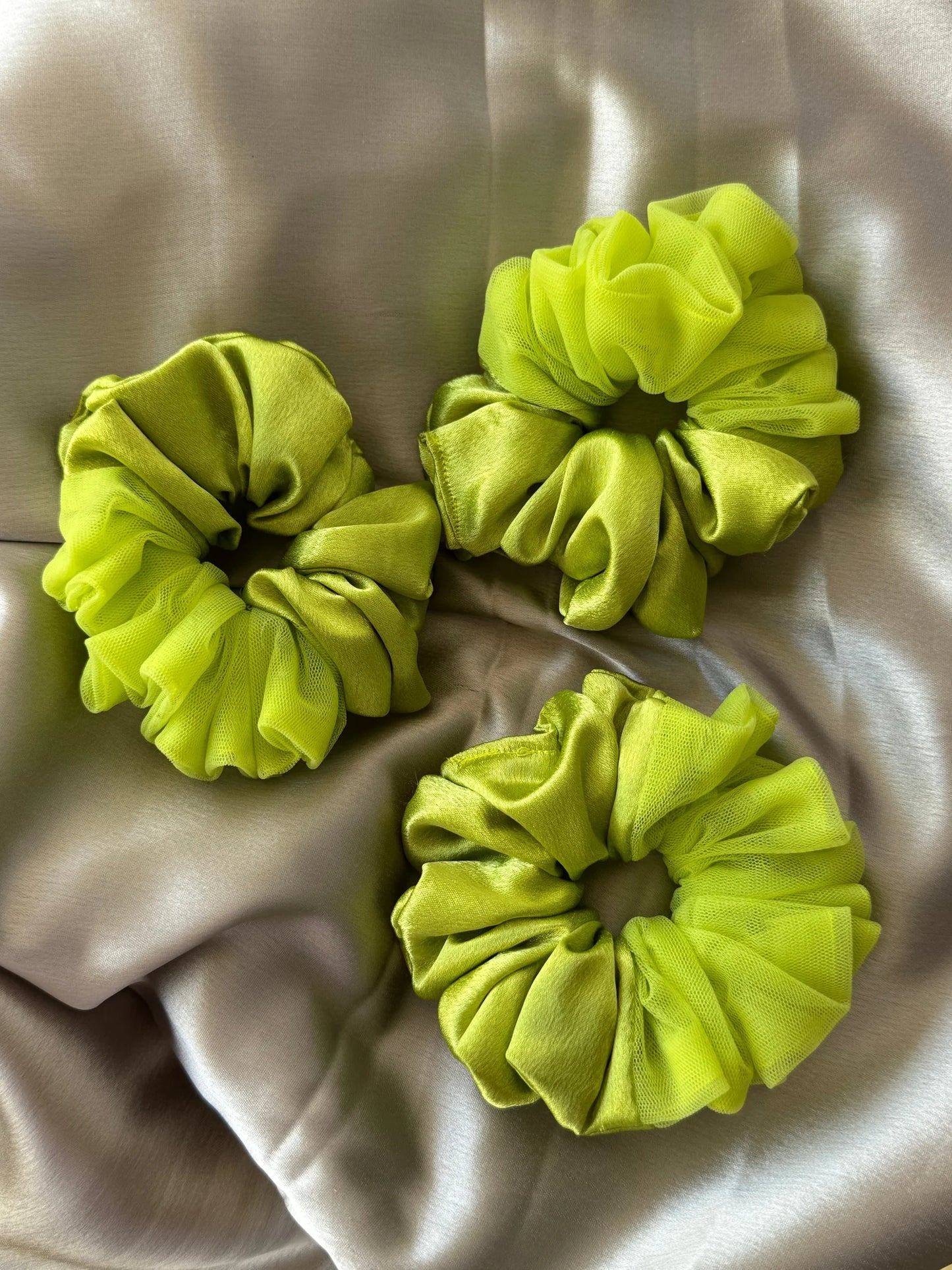 Three neon green satin and net scrunchies by Bows and Bags India displayed on cream fabric, showing handmade hair accessory