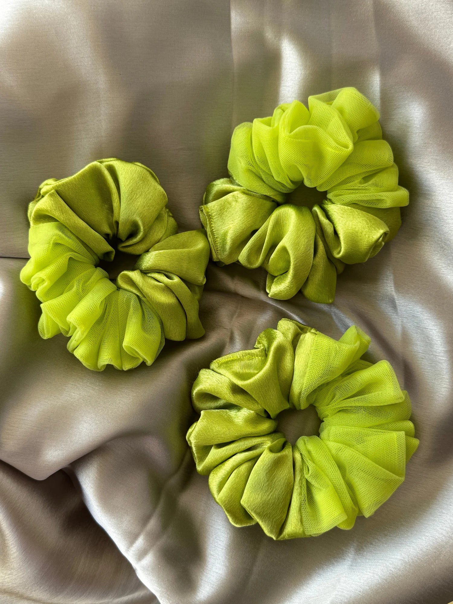 Three neon green satin and net scrunchies by Bows and Bags India displayed on cream fabric, showing handmade hair accessory