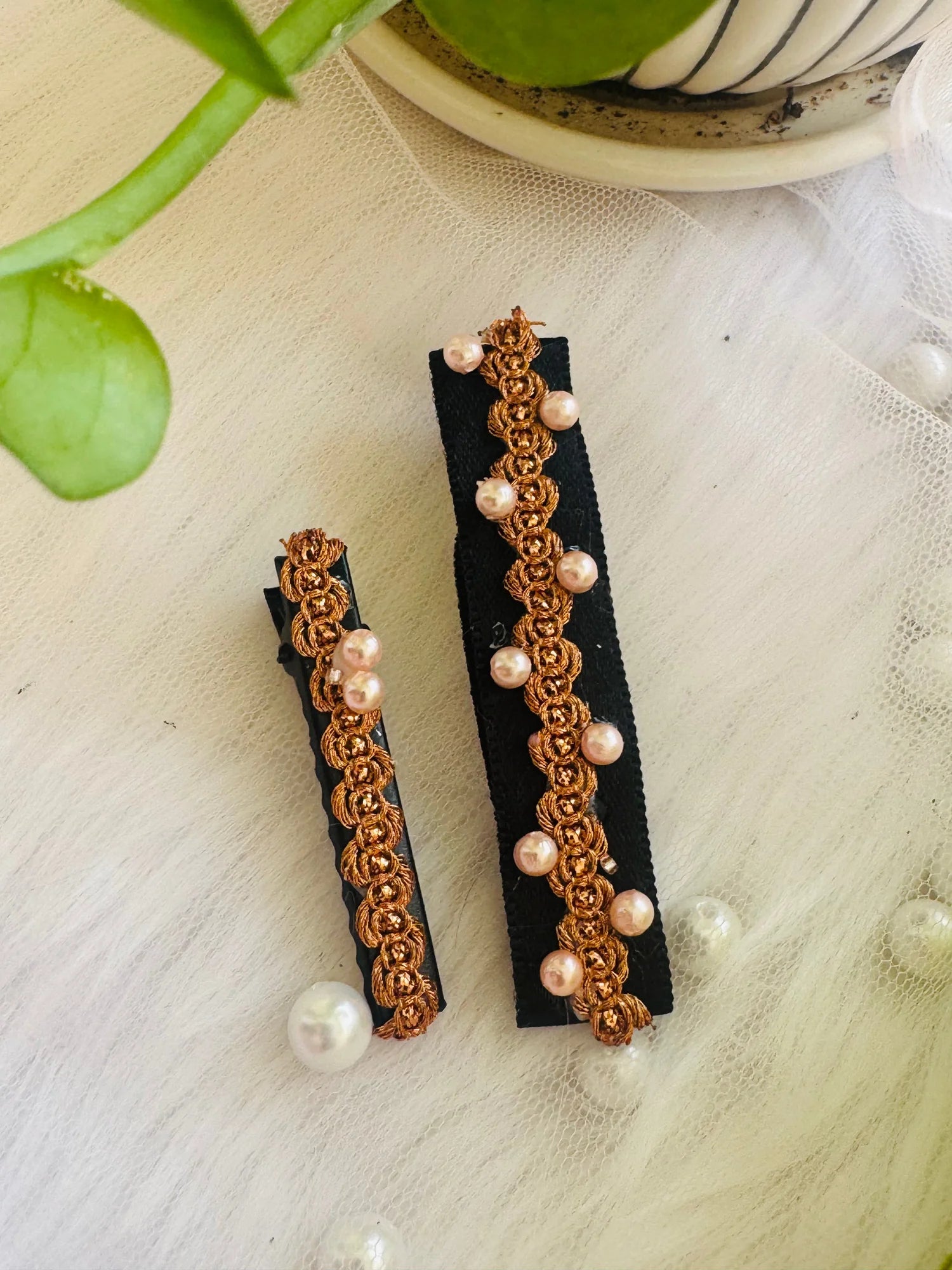 Two pearl-embroidered golden hair clips on black velvet by Bows and Bags India, detailed handmade accessory display