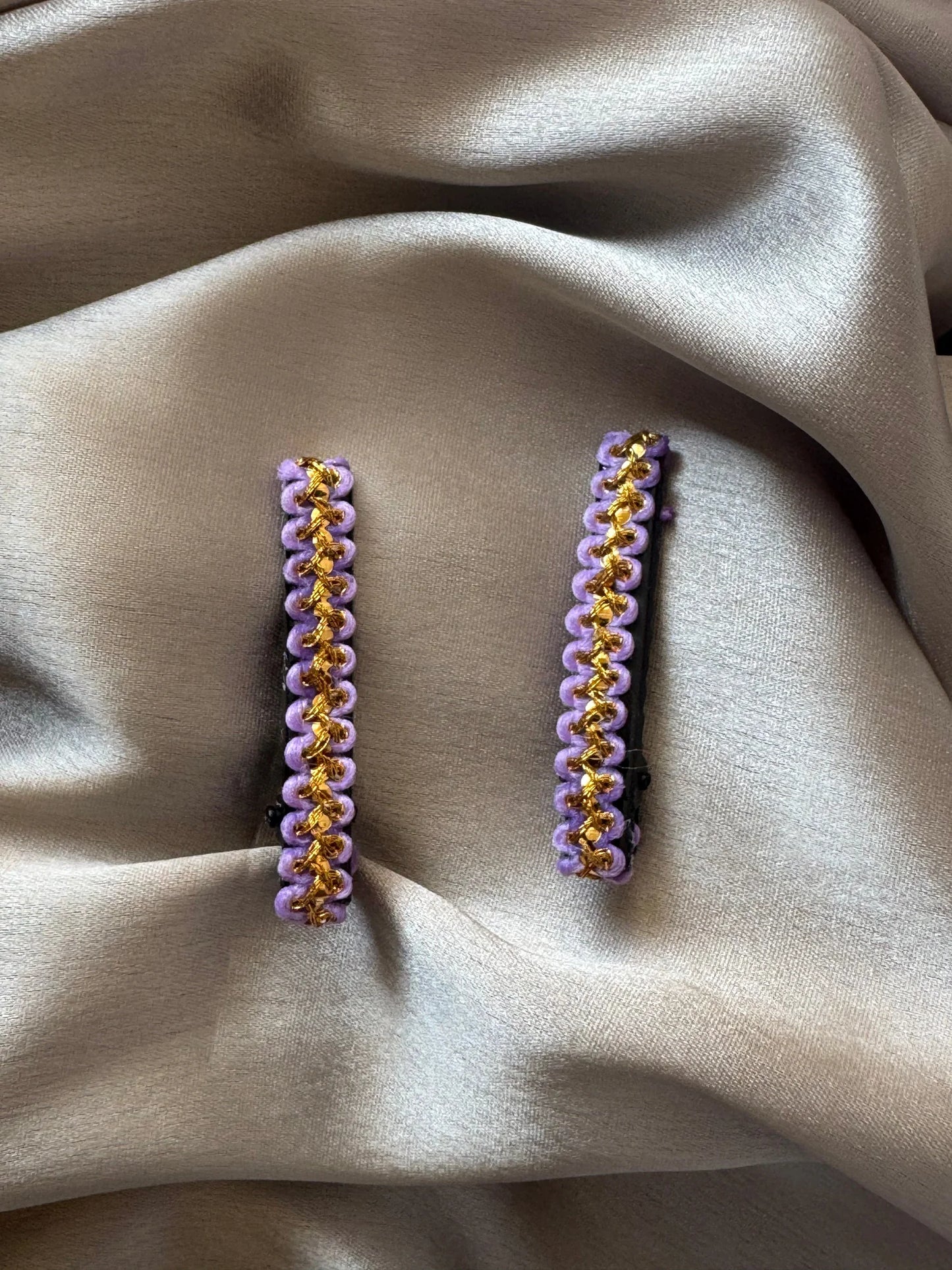 Pair of lavender and gold handmade hair clips by Bows and Bags India displayed on neutral fabric, showing intricate beaded