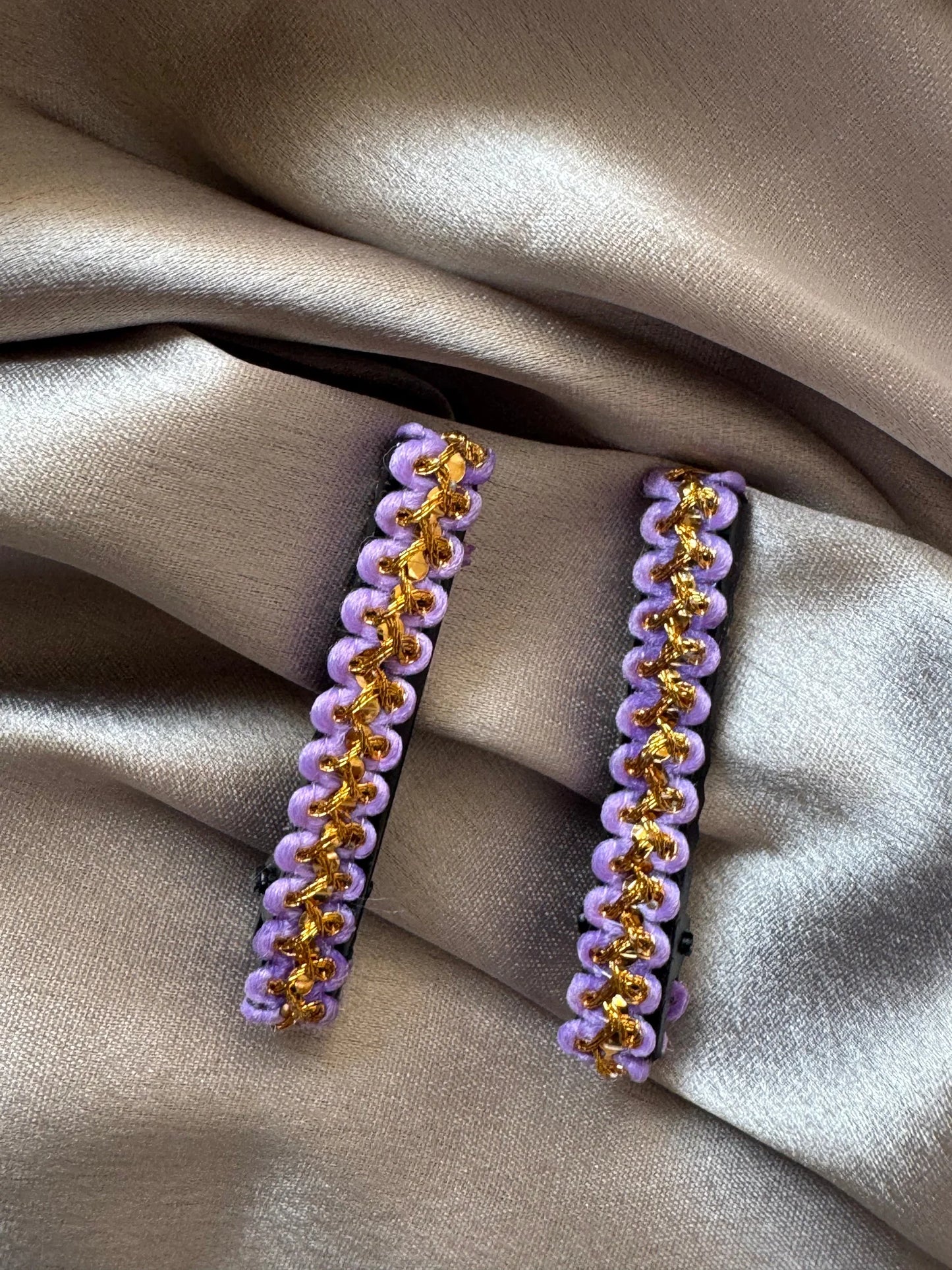 Pair of lavender and gold beaded handmade hair clips by Bows and Bags India on neutral fabric, close-up detail view