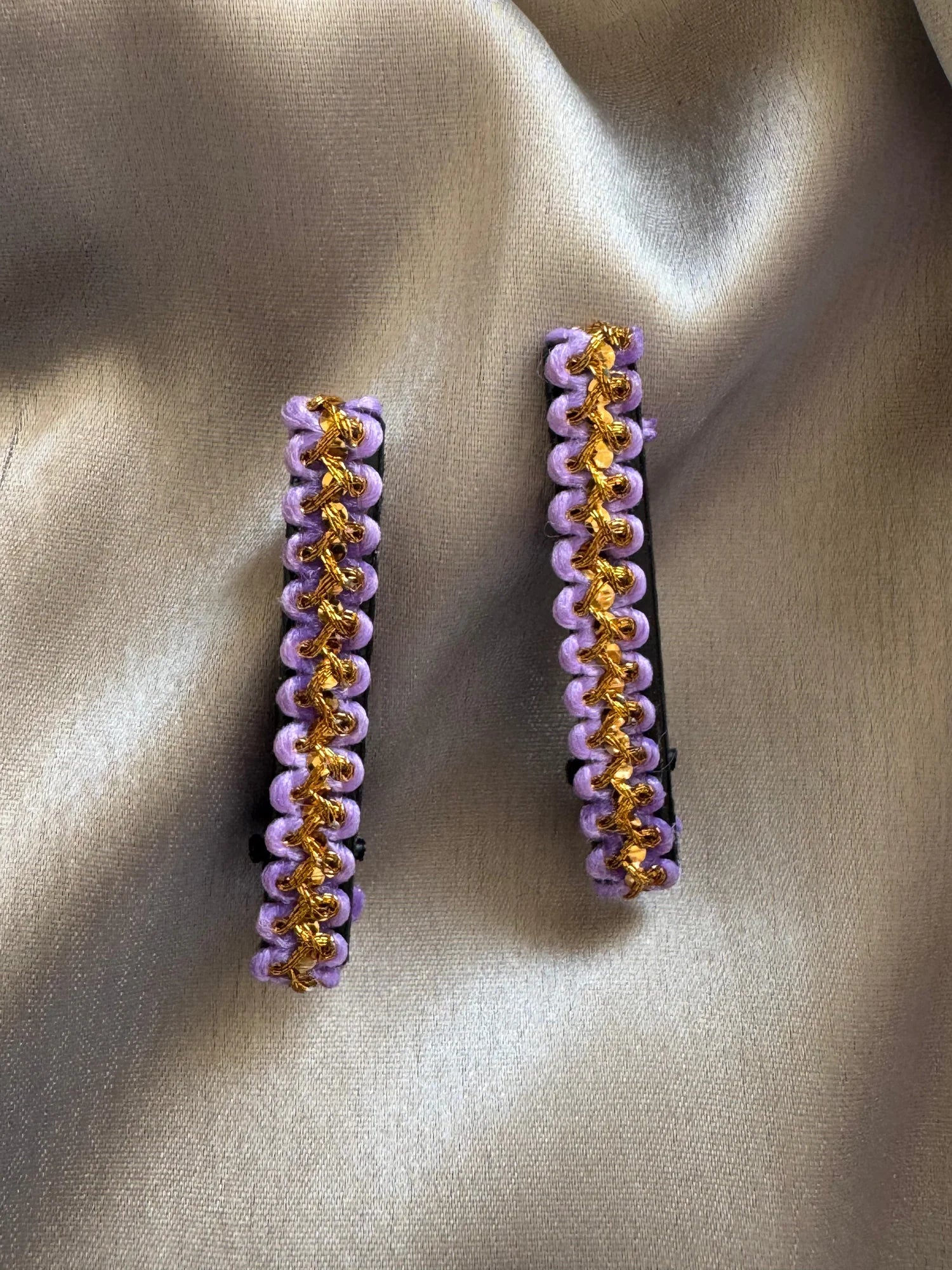 Pair of lavender and gold handmade hair clips by Bows and Bags India displayed on neutral fabric background
