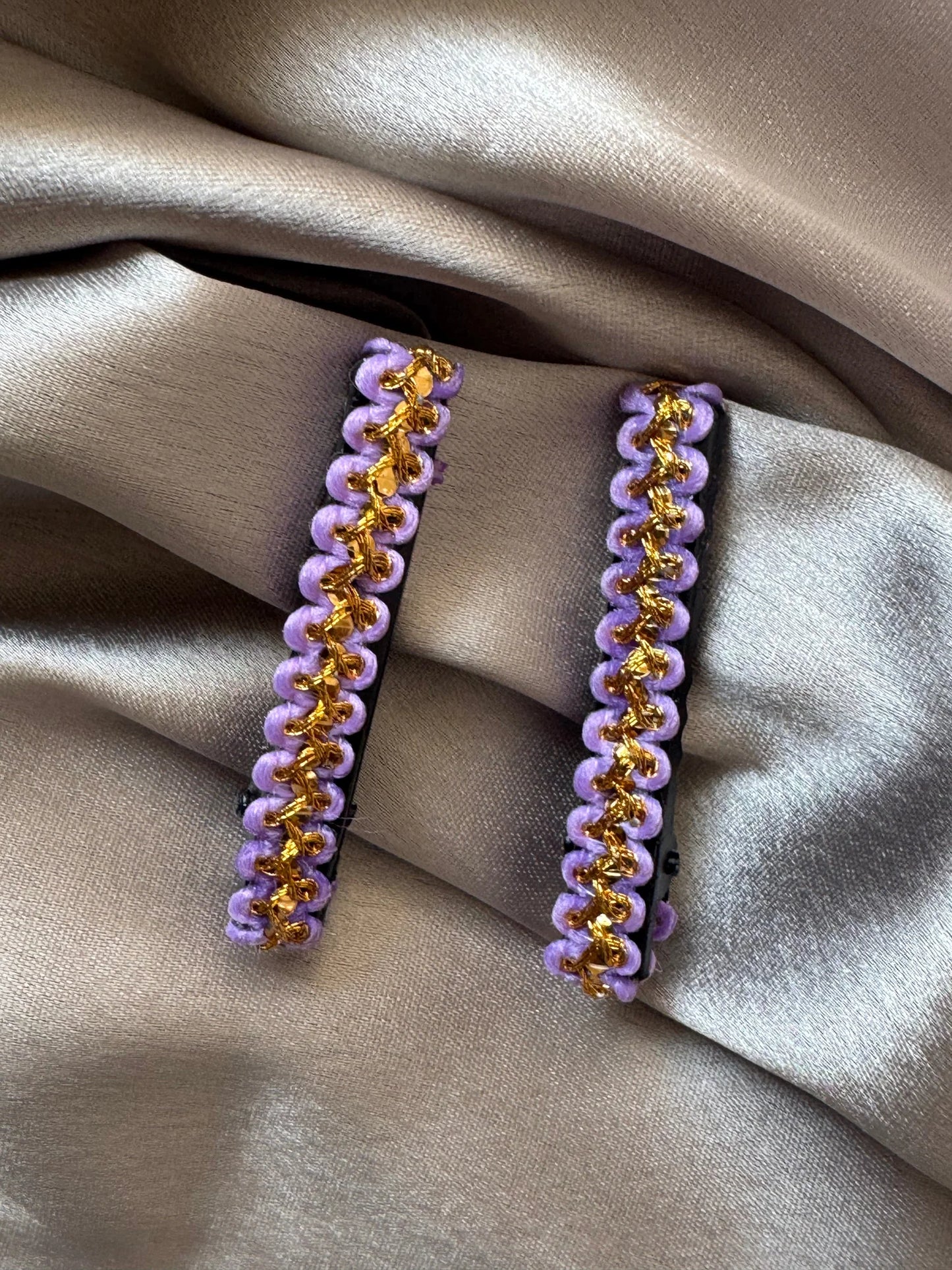 Pair of lavender and gold handmade hair clips by Bows and Bags India displayed on neutral fabric, showing intricate beaded