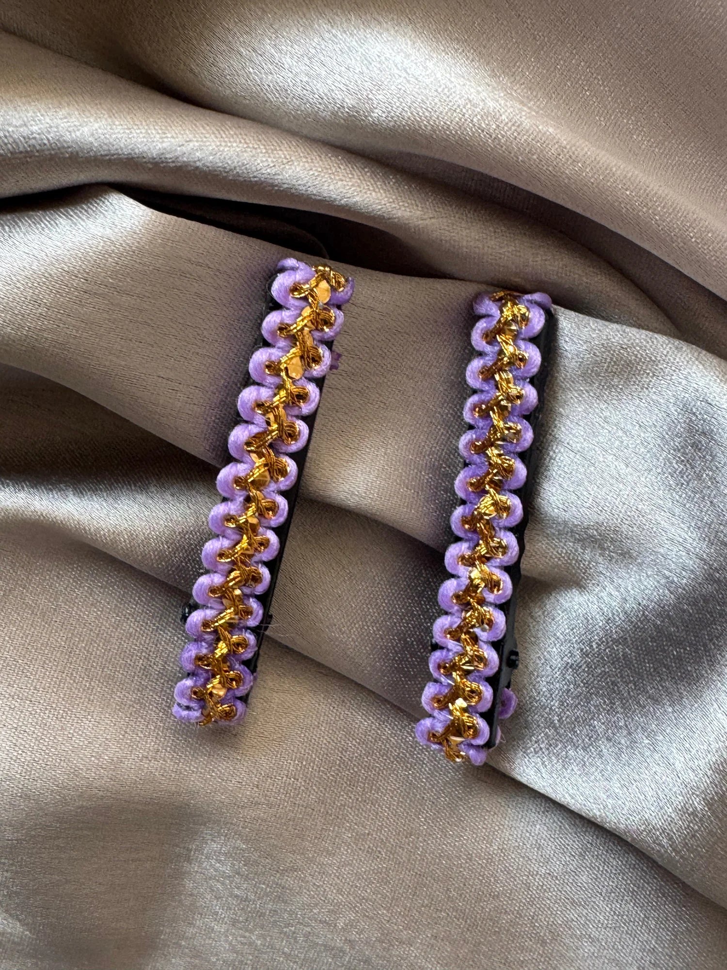 Pair of lavender and gold handmade hair clips by Bows and Bags India displayed on neutral fabric, showing intricate beaded
