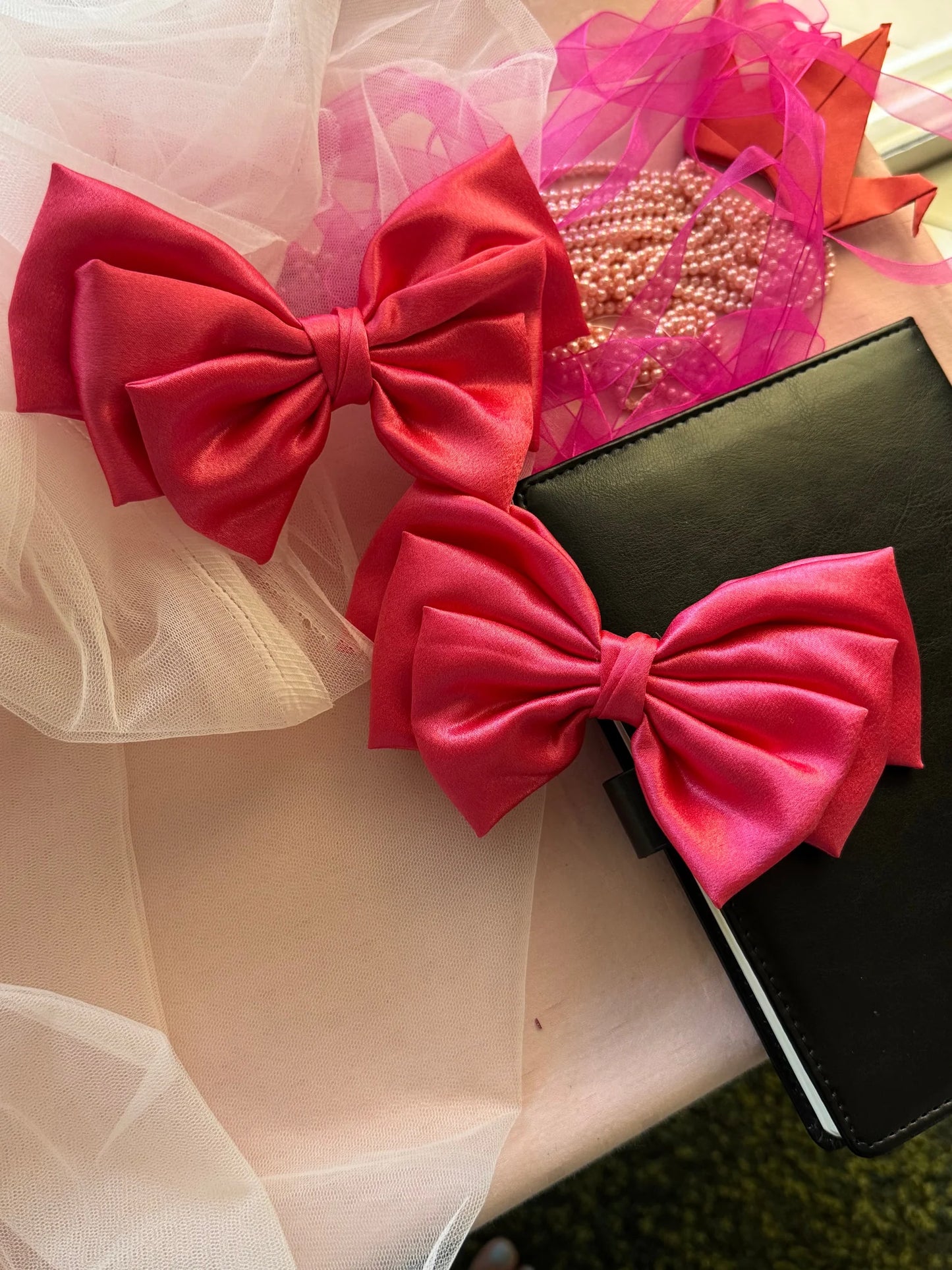 Hot pink satin hair bow by Bows and Bags India with pearl beads and tulle, handmade hair accessory styled with black clutch